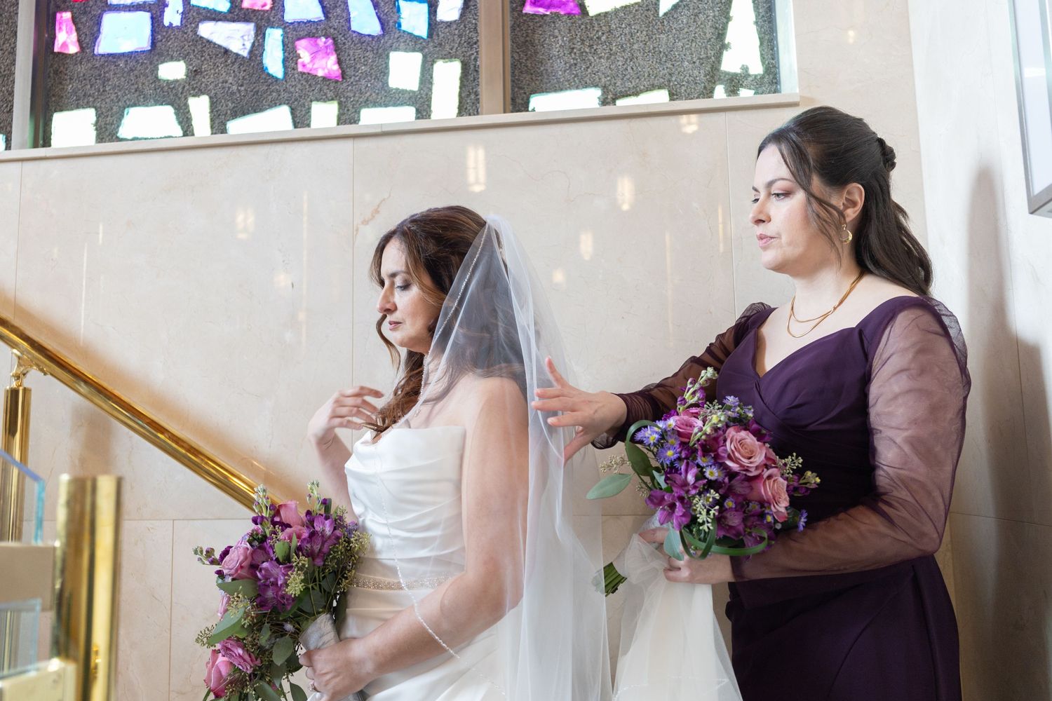 Wedding party members with purple floral bouquets preparing for ceremony.