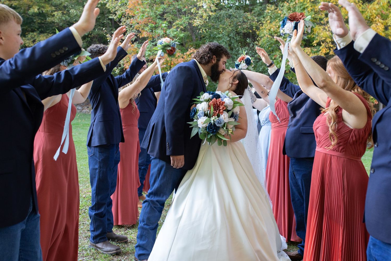 Wedding party creates an arch with raised arms as newlyweds walk beneath.