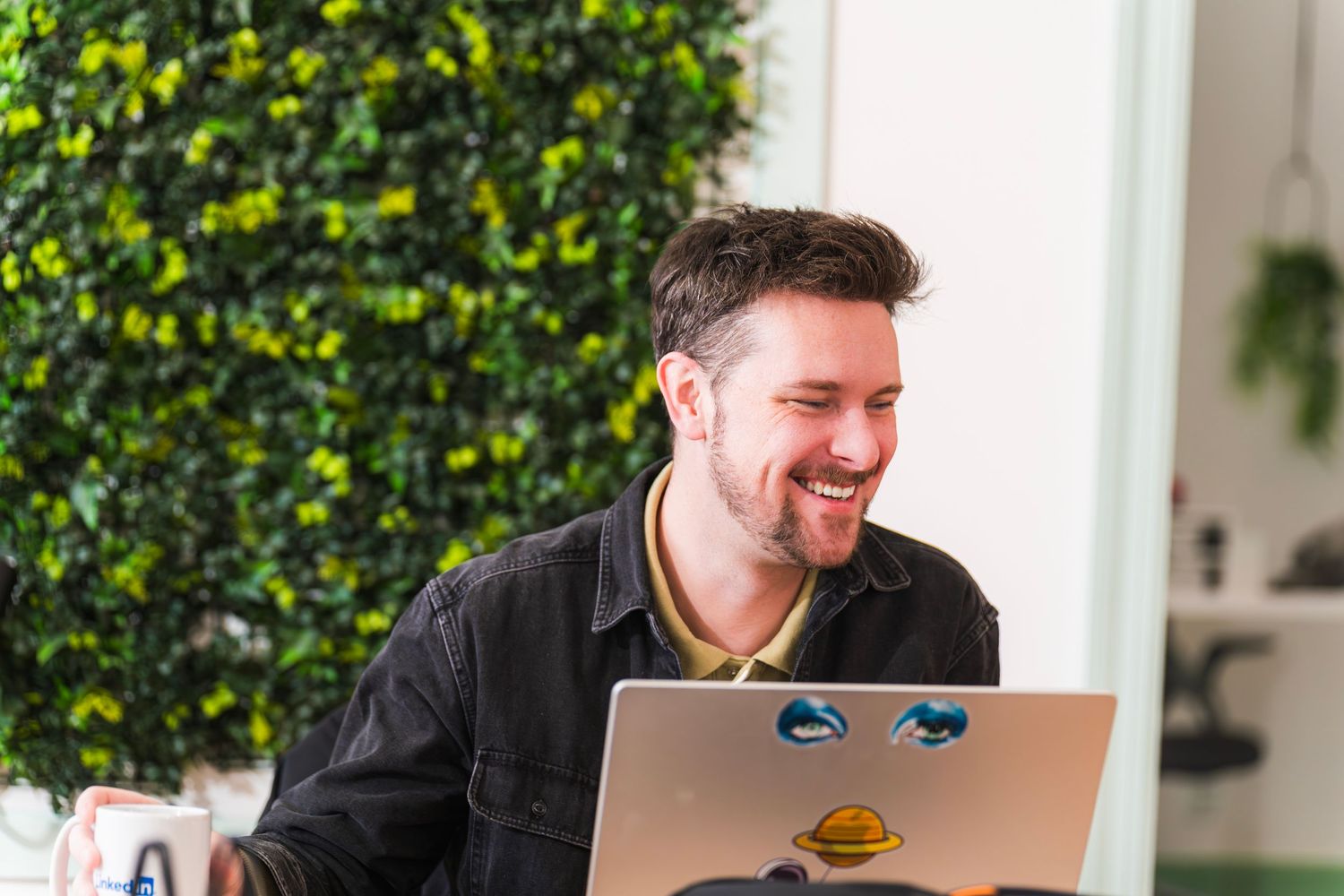 Two colleagues having a casual discussion with coffee mugs on a couch in a bright office.