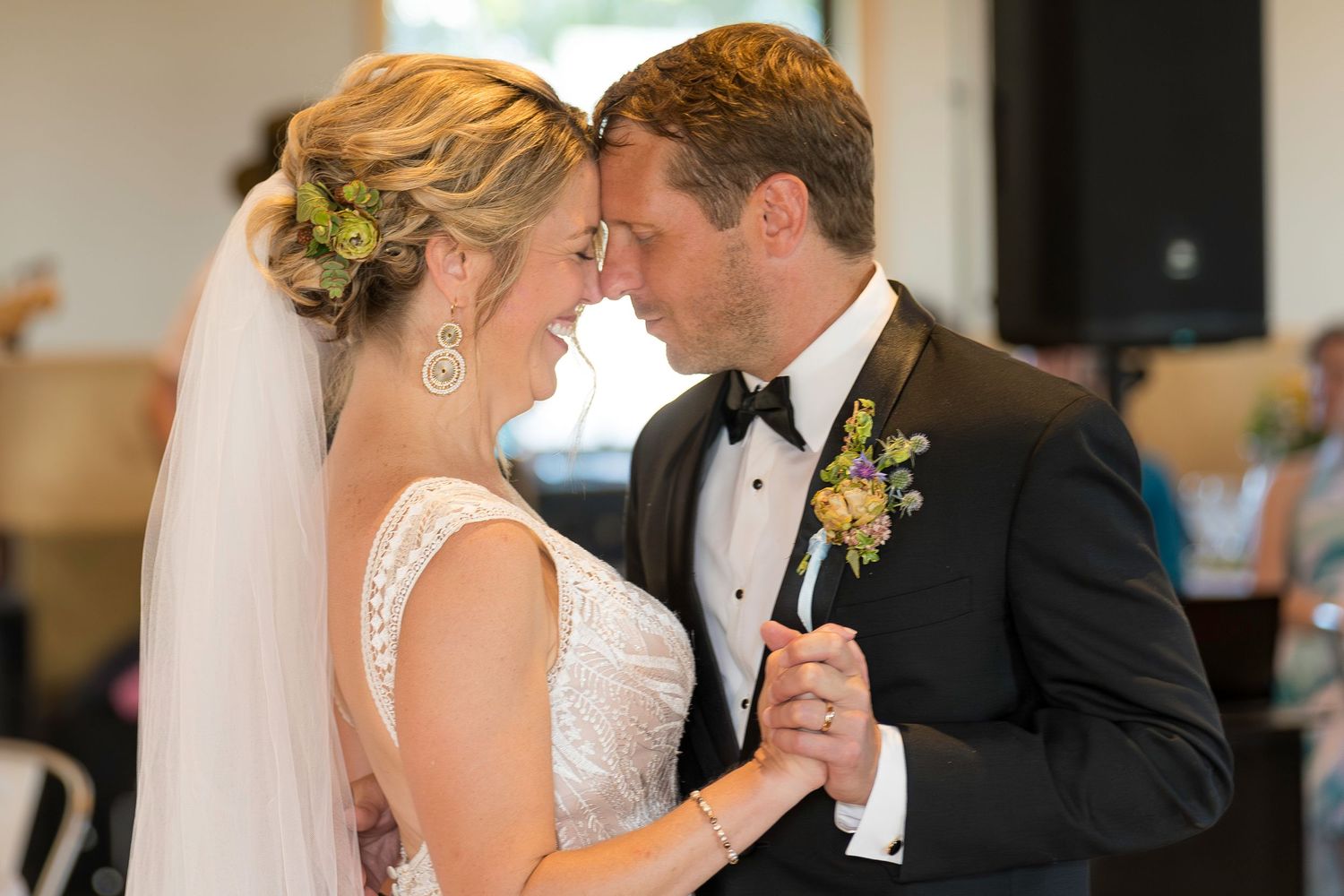 Bride and groom share an intimate first dance moment, touching foreheads tenderly at their wedding.