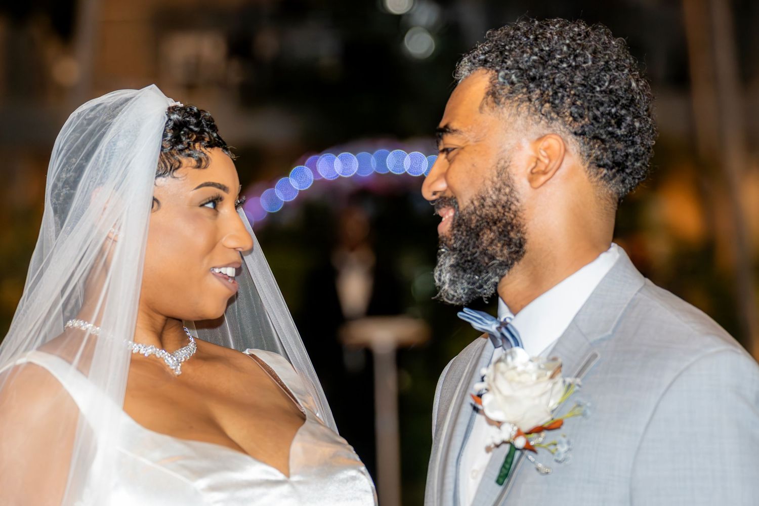 Bride and groom gaze into each others eyes outdoors at night after wedding ceremony.