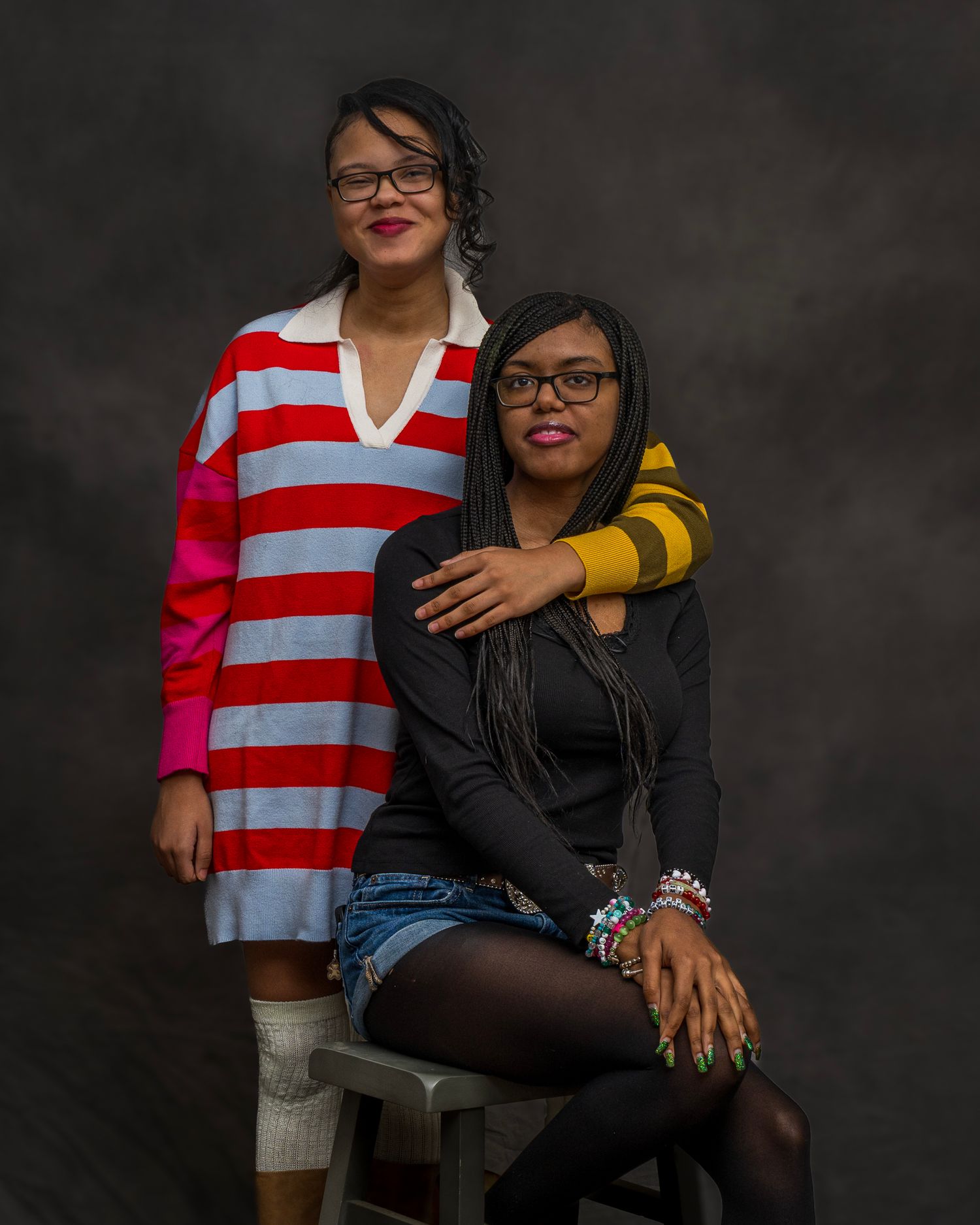 Two young Black women in colorful outfits pose in professional studio portrait.