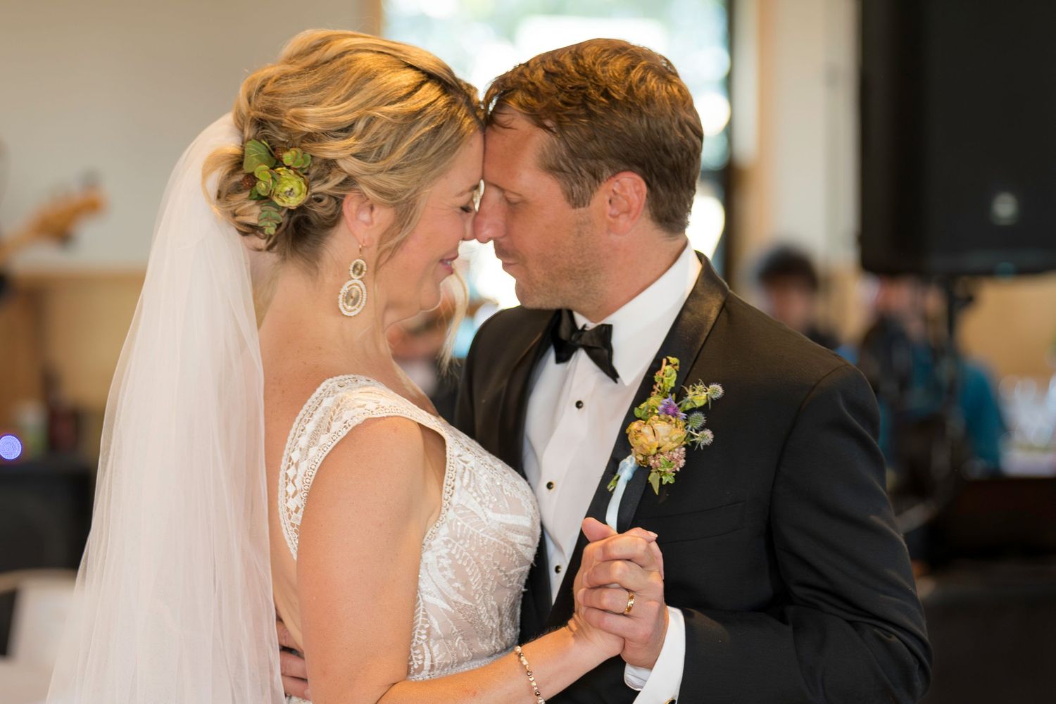 Bride and groom sharing intimate forehead touch during romantic first dance at wedding reception.