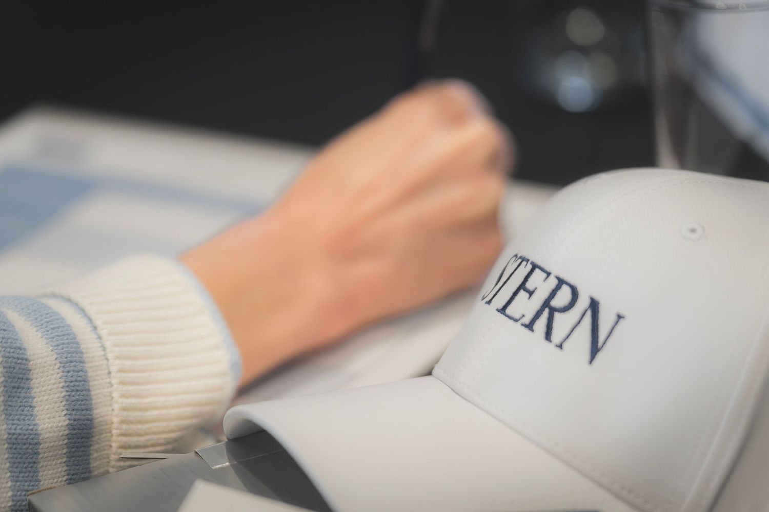 Close-up of white cap with INTERN text on conference table during business meeting.