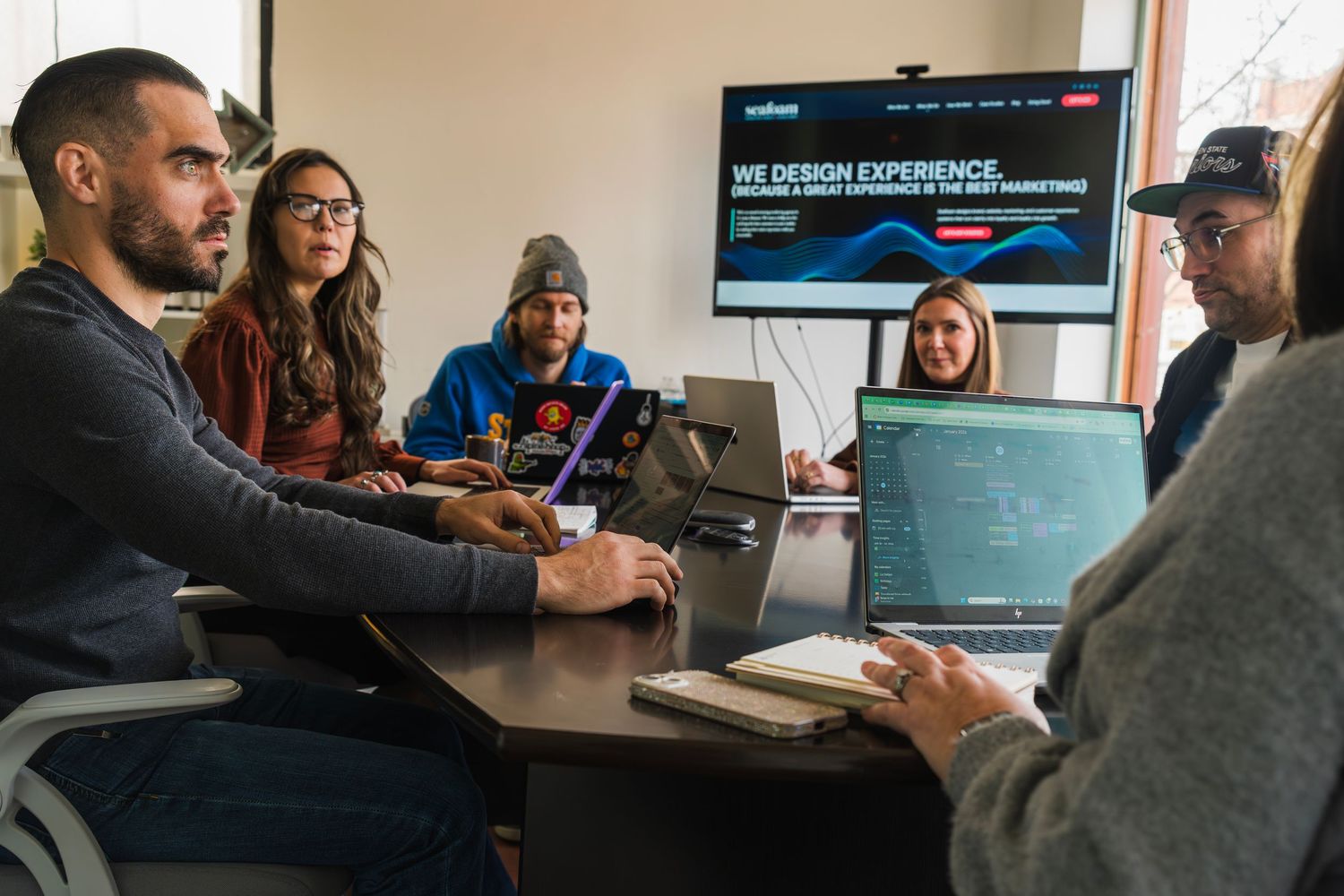Team collaborating around a conference table with laptops and a presentation screen in a modern office.