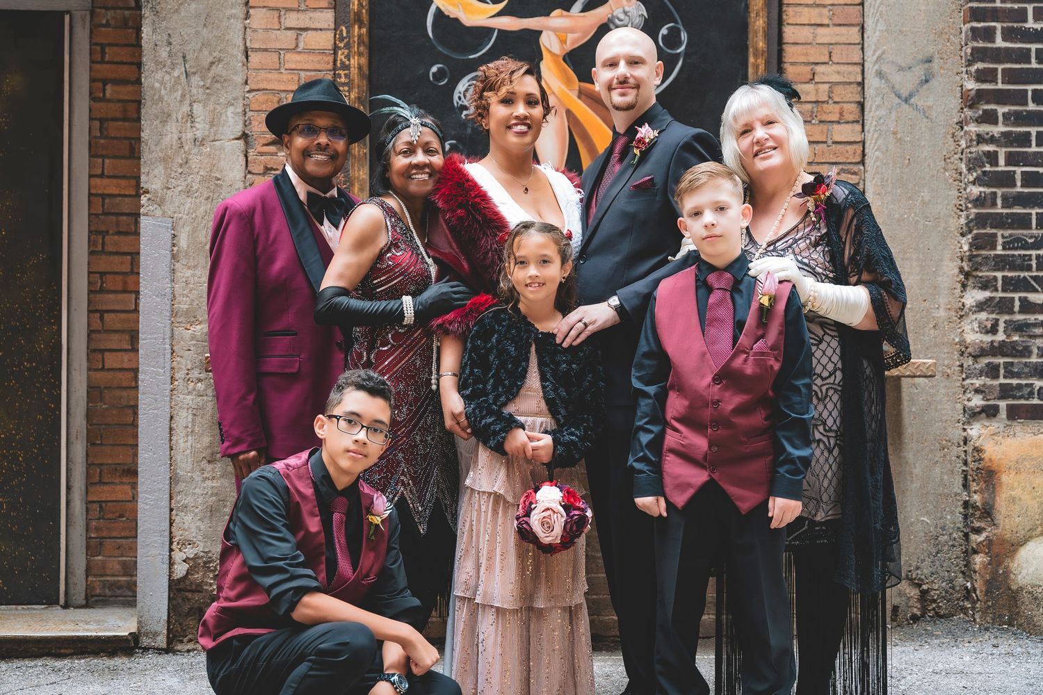 Family group posing together in vintage 1920s-inspired formal attire in an urban alleyway setting.