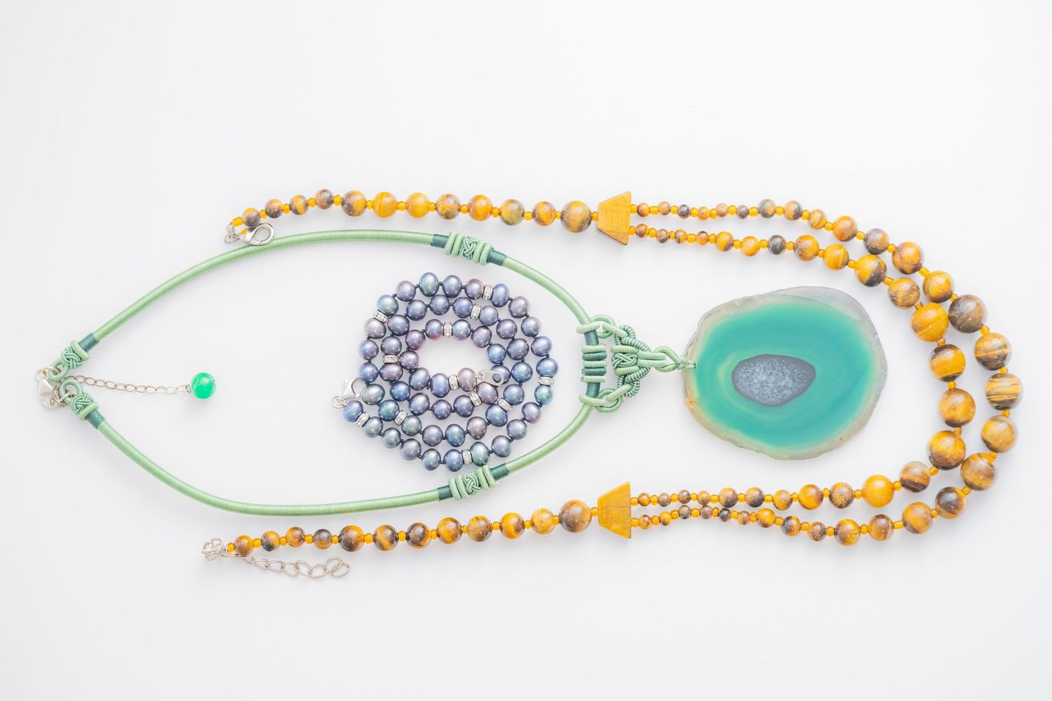 Flat lay of gemstone necklaces featuring tiger eye beads and teal agate pendant.