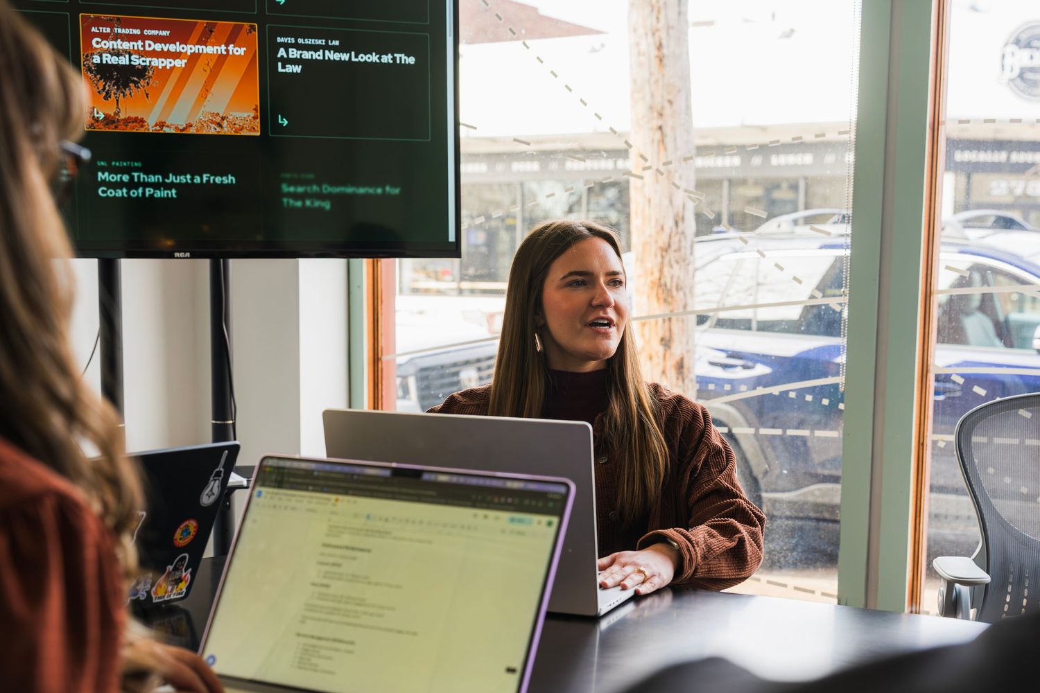 Two colleagues reviewing work on an HP laptop at a Seafoam branded office space.