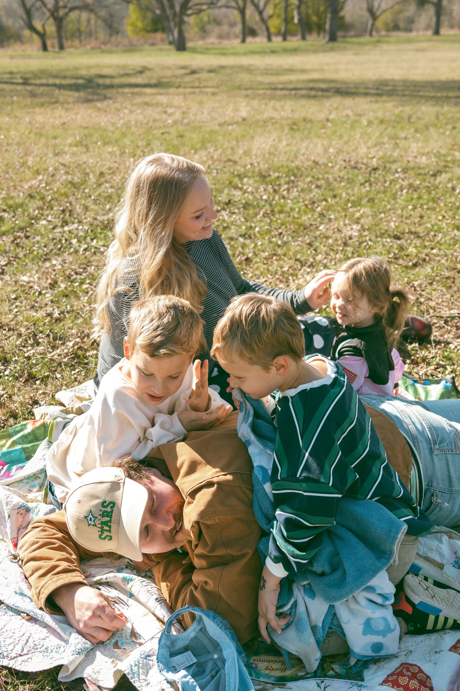 Children and a puppy having fun together while relaxing on a blanket outdoors on a sunny autumn day.