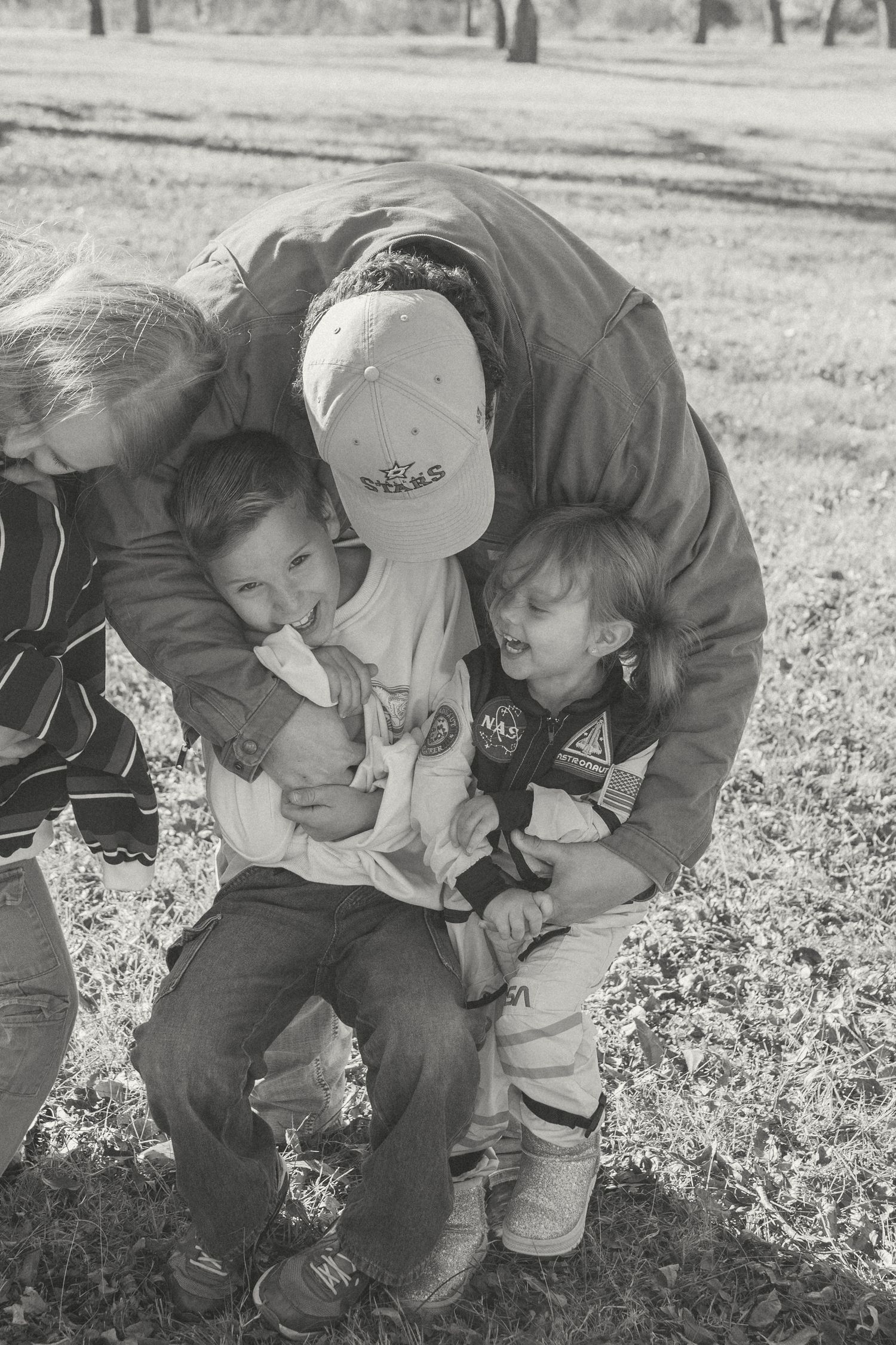 A series of black and white photos showing a parent bending down to comfort a small child in a field.