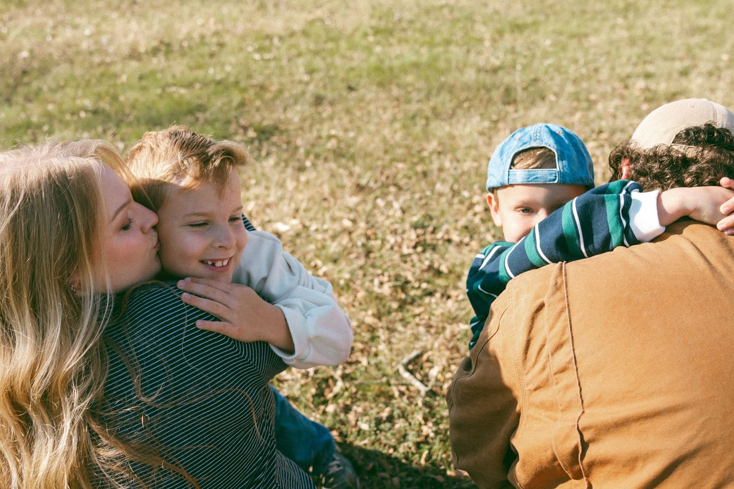 Family enjoying a tender moment together while relaxing outdoors on an autumn day.