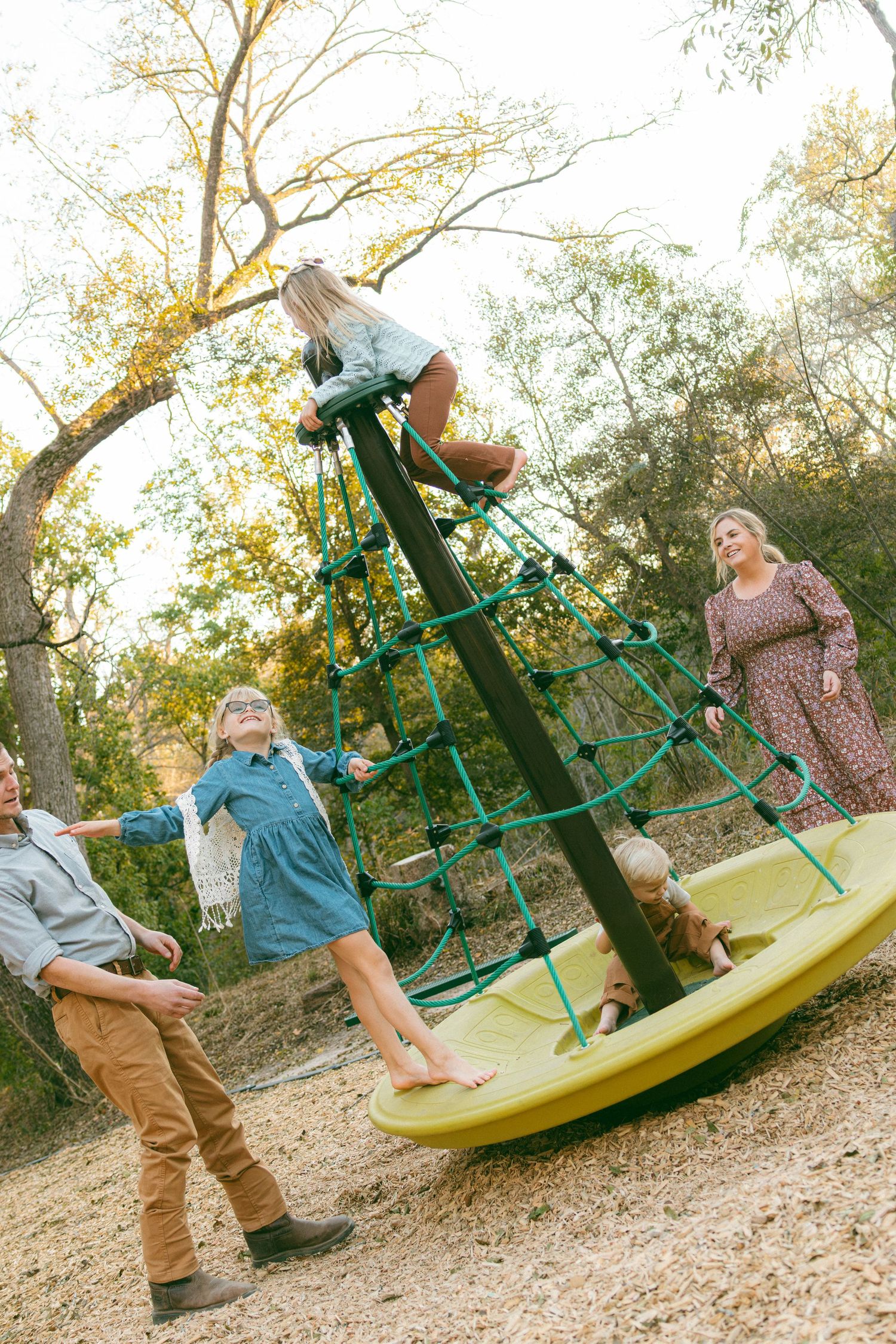 A sequence of four photos showing a child spinning on a yellow playground merry-go-round in a park setting.