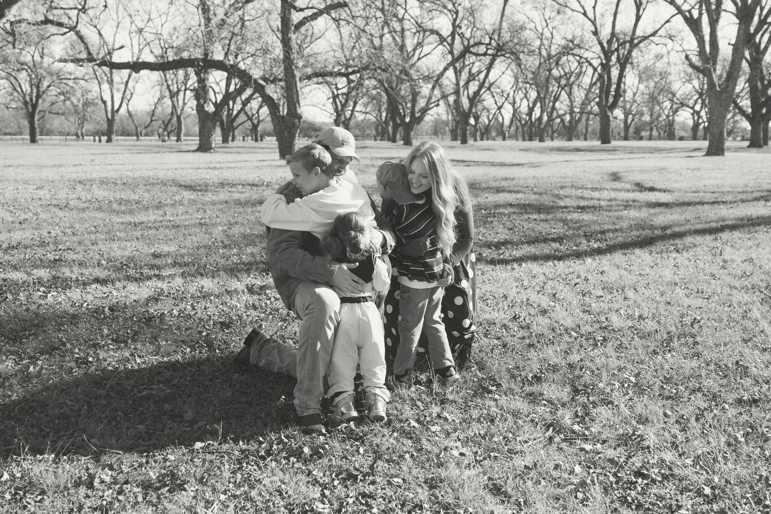 Vintage black and white photograph of people playing with dogs in a grassy field on a winter day.