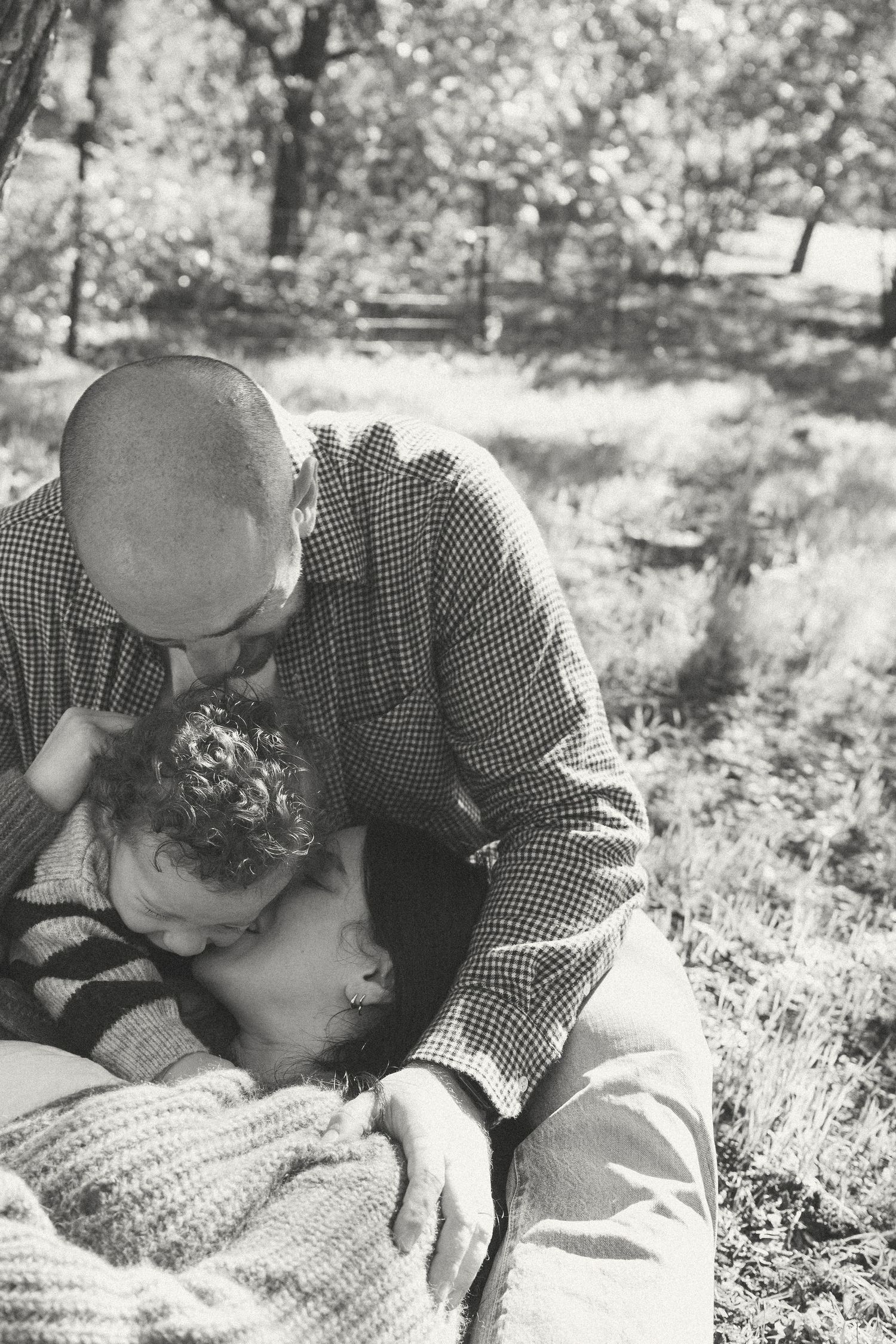 A couple shares a tender moment lying together outdoors in black and white vintage photography.