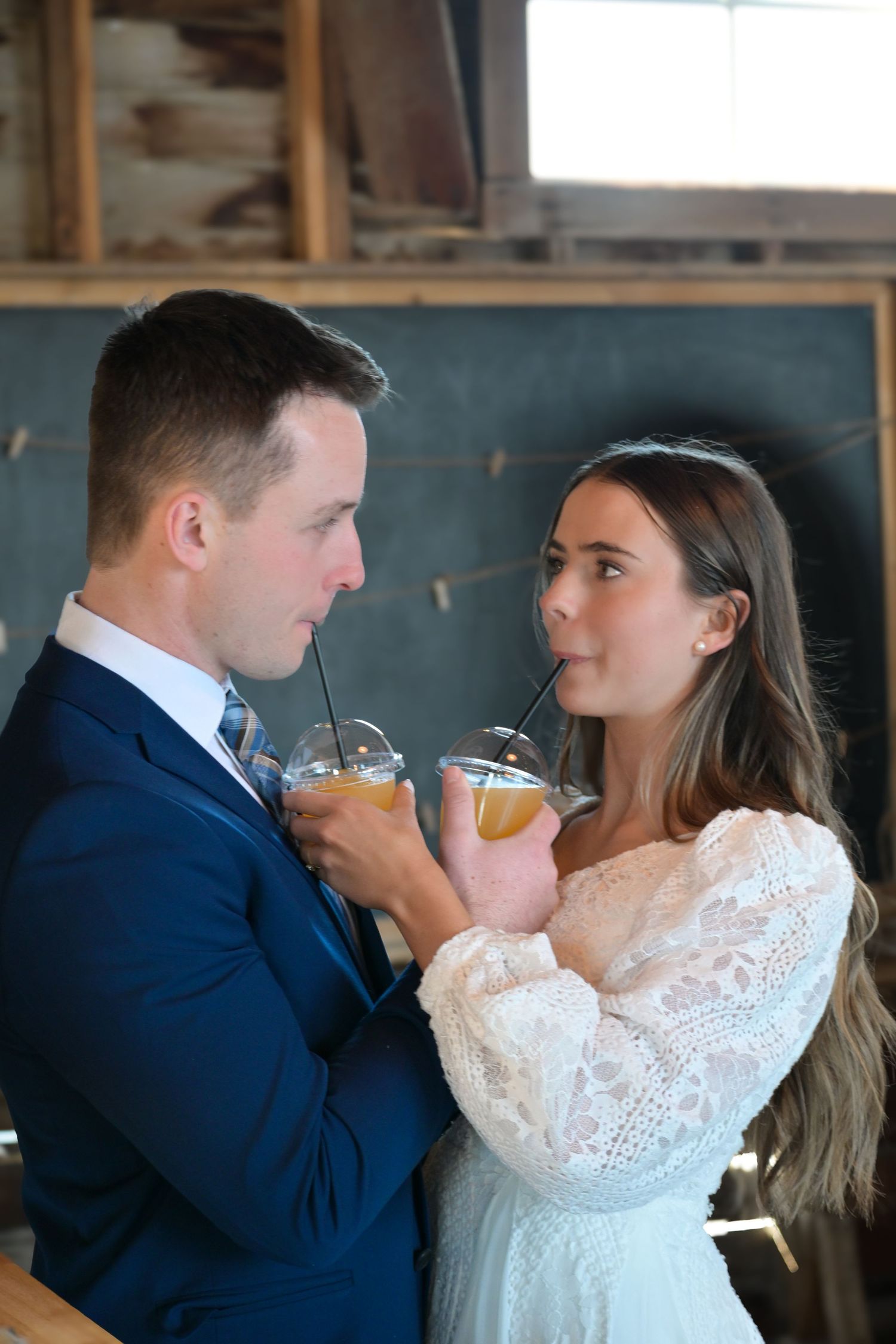 Couple shares intimate moment with cocktails at rustic indoor reception venue.