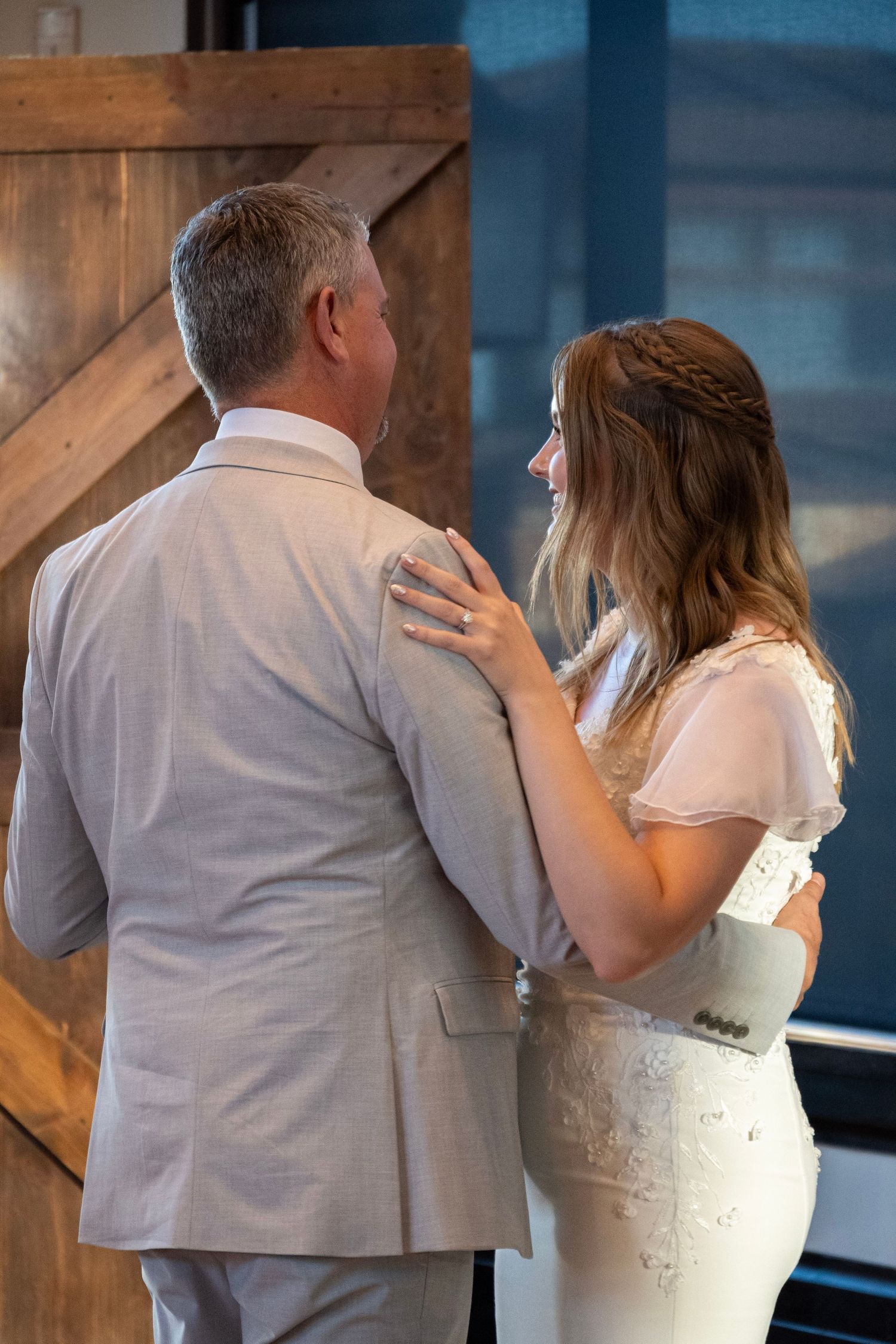 A tender moment captured during a wedding dance on a hardwood floor with rustic decor.