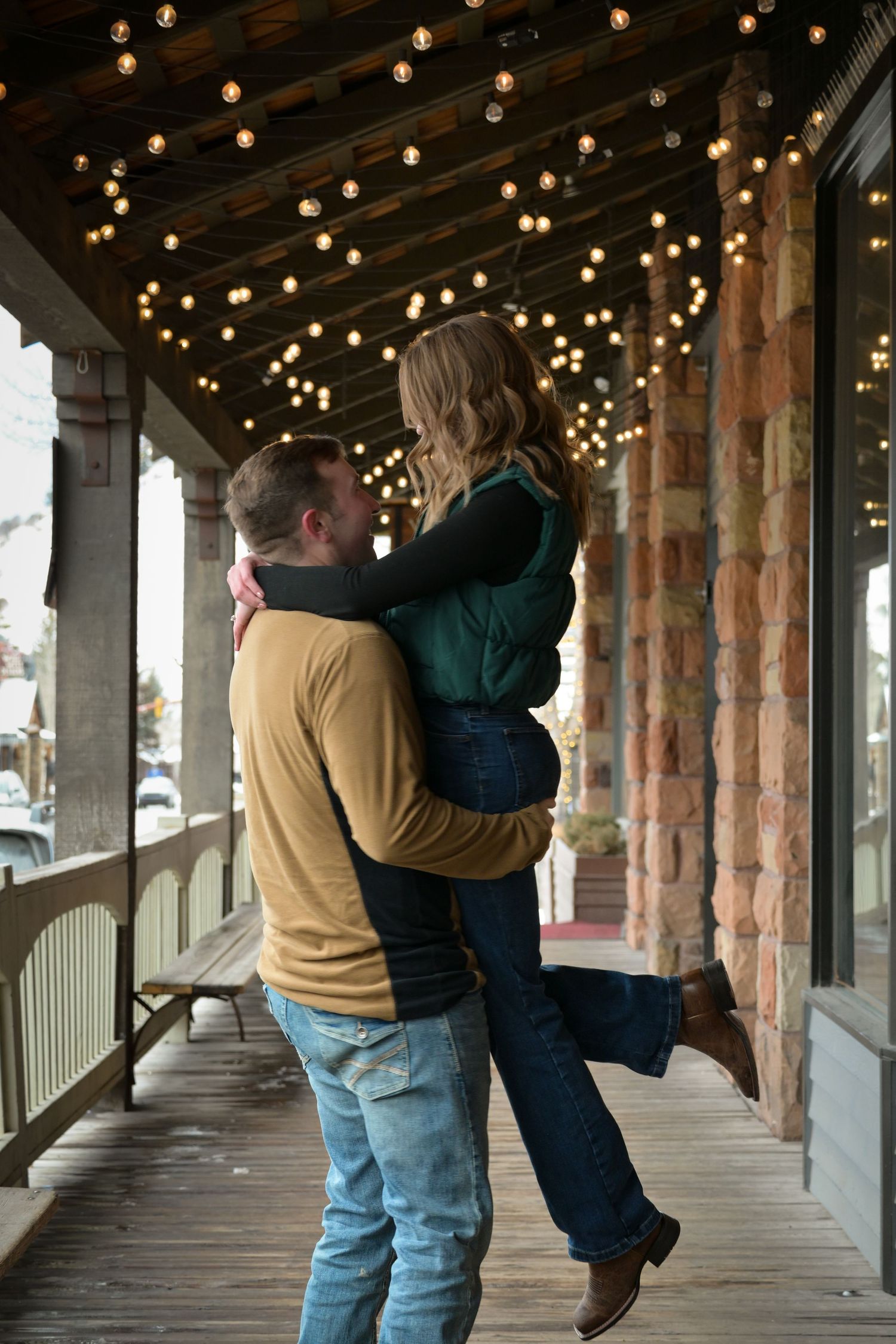 Romantic couple moment under twinkling lights on a rustic porch.
