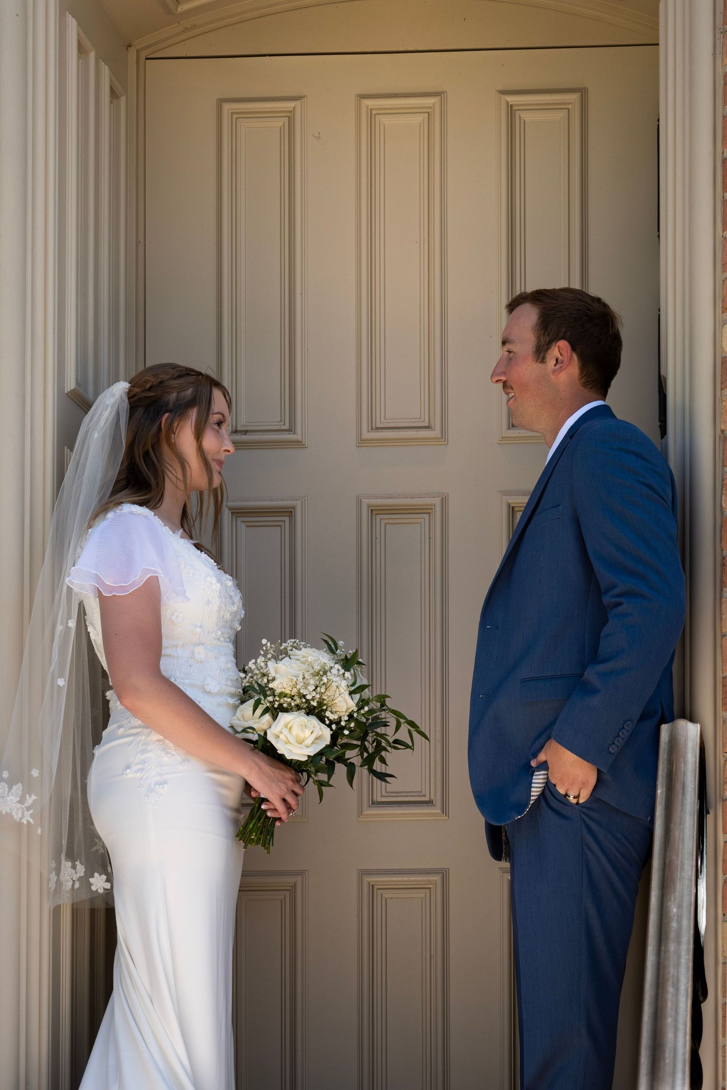 A wedding first look sequence showing moments of anticipation in front of elegant cream-colored doors.