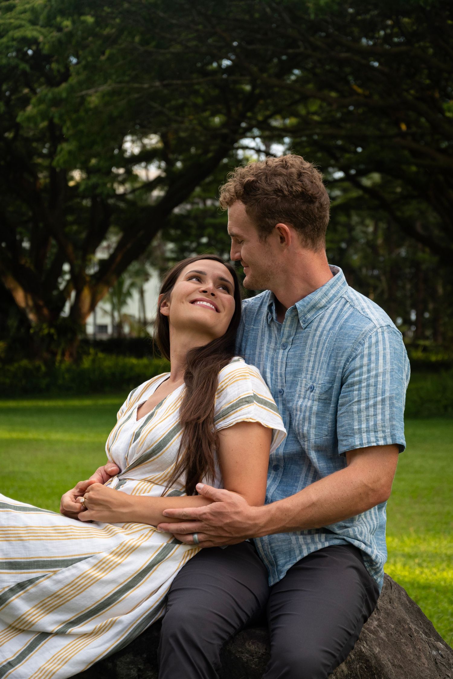 Romantic couple shares intimate moments on outdoor park bench while cuddling under a blanket.