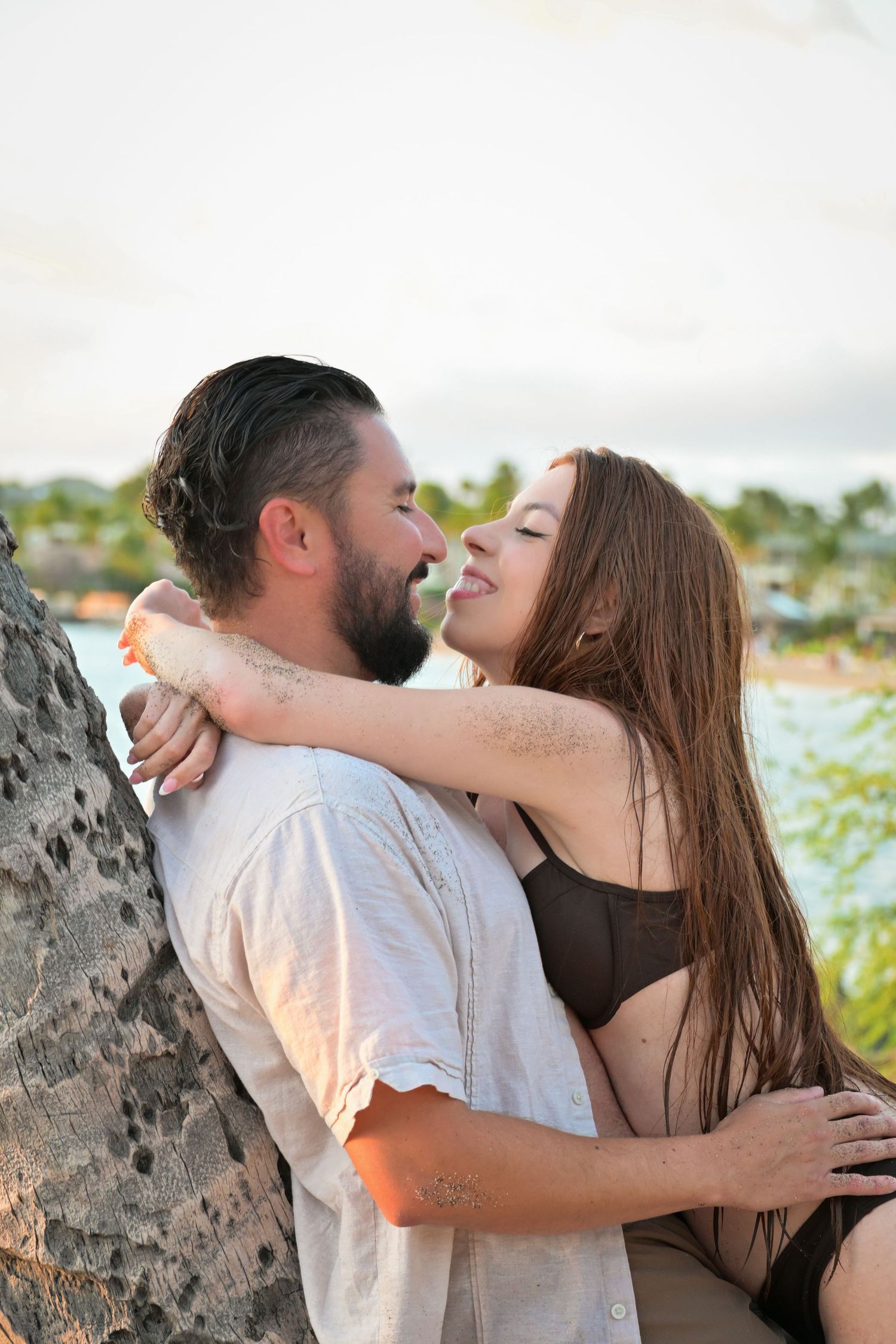 Romantic couple sharing tender kisses against a rustic backdrop in warm sunlight.