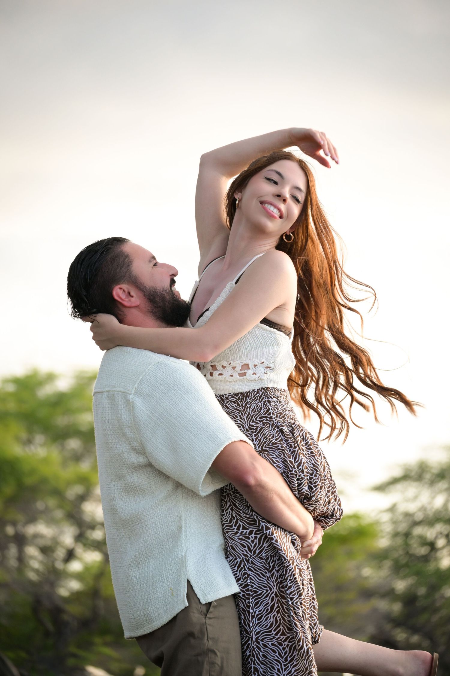 A couple embraces intimately in a series of romantic dance poses against a soft sunset backdrop.