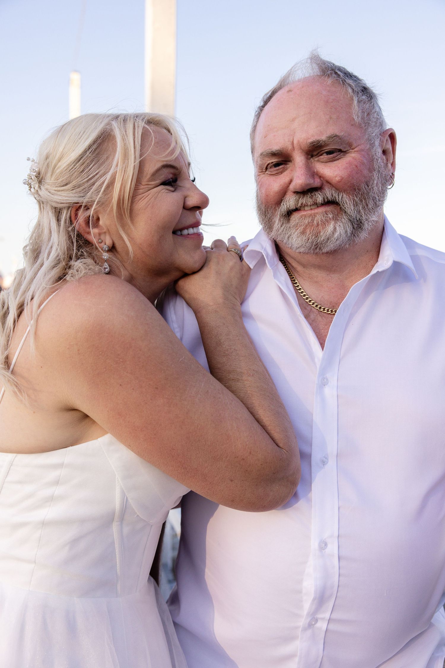 A couple in white clothing share tender moments in a series of romantic poses against a light background.