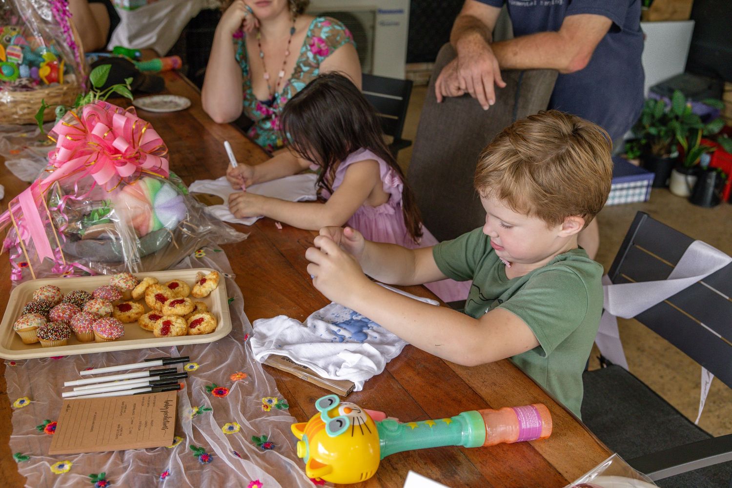 Children sitting at a table with cookies and craft supplies at a birthday party celebration.