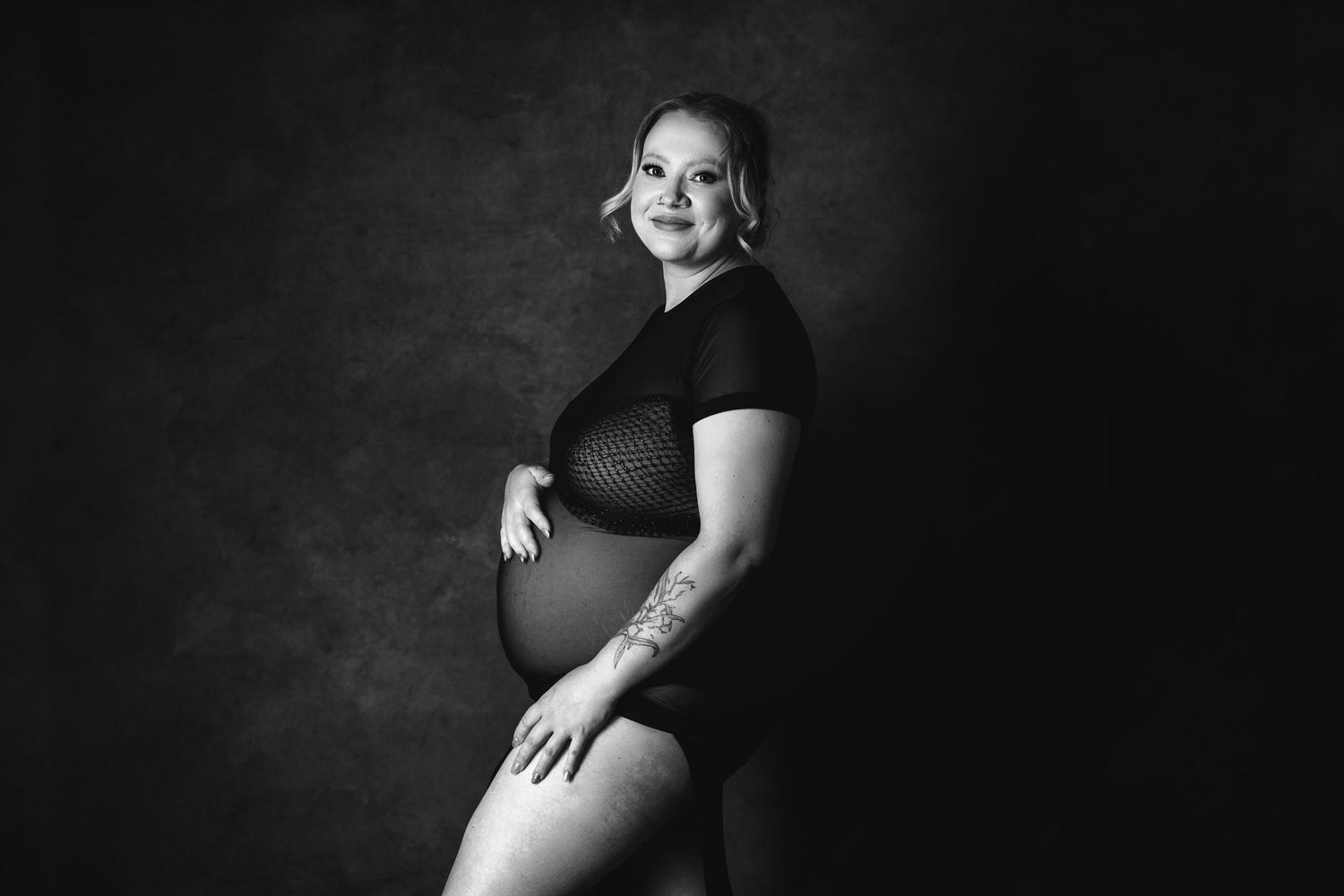 A dramatic black and white maternity photo series showing different poses of an expectant mother against a dark background.