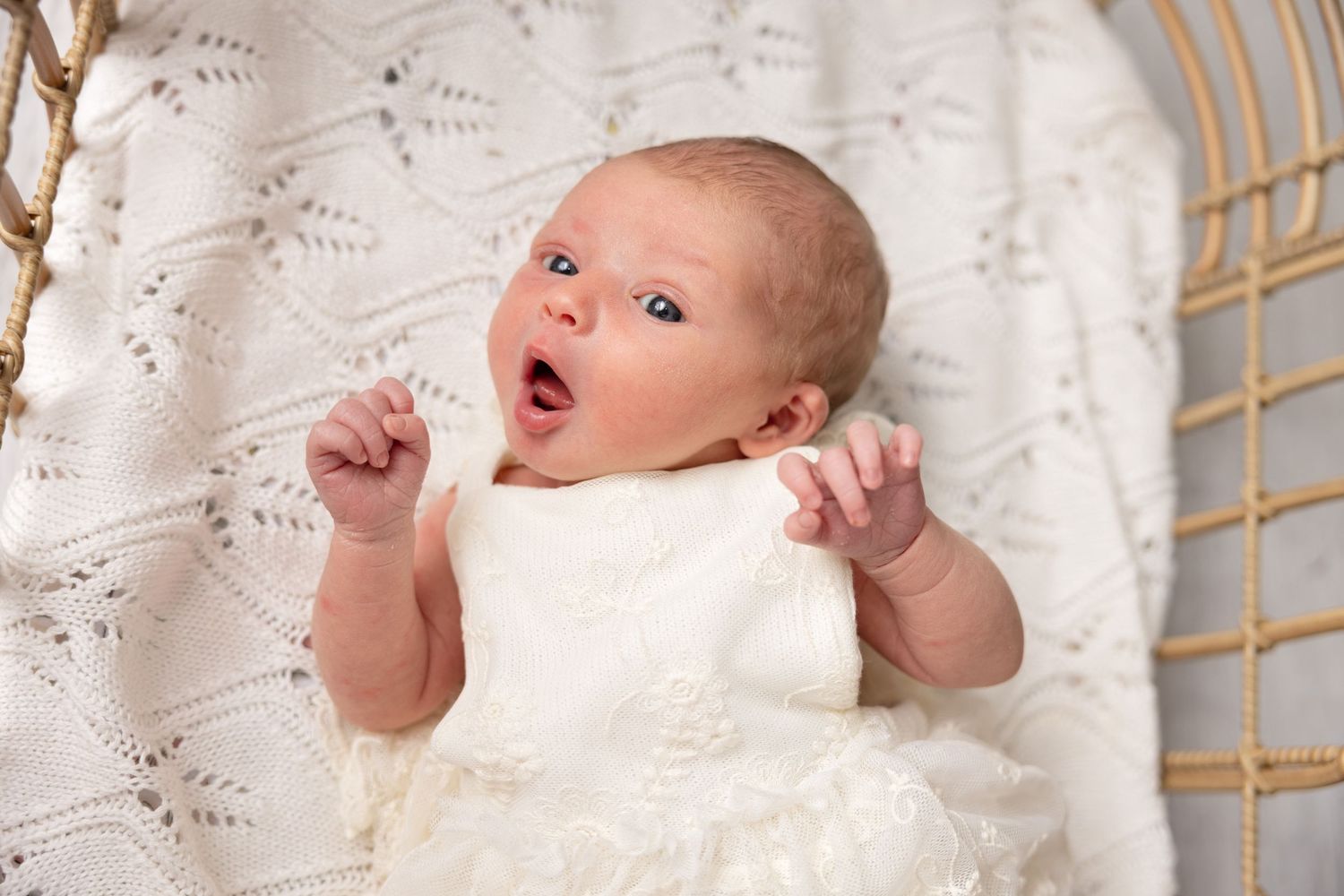 A series of four connected photos showing a baby in white clothing against a white lace backdrop.