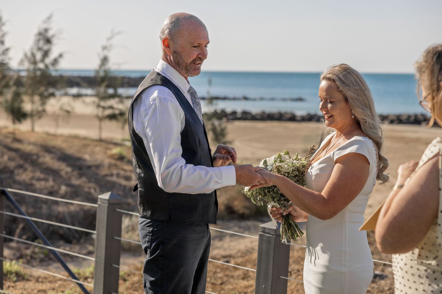 A couple shares an intimate moment during their beach wedding ceremony at sunset.