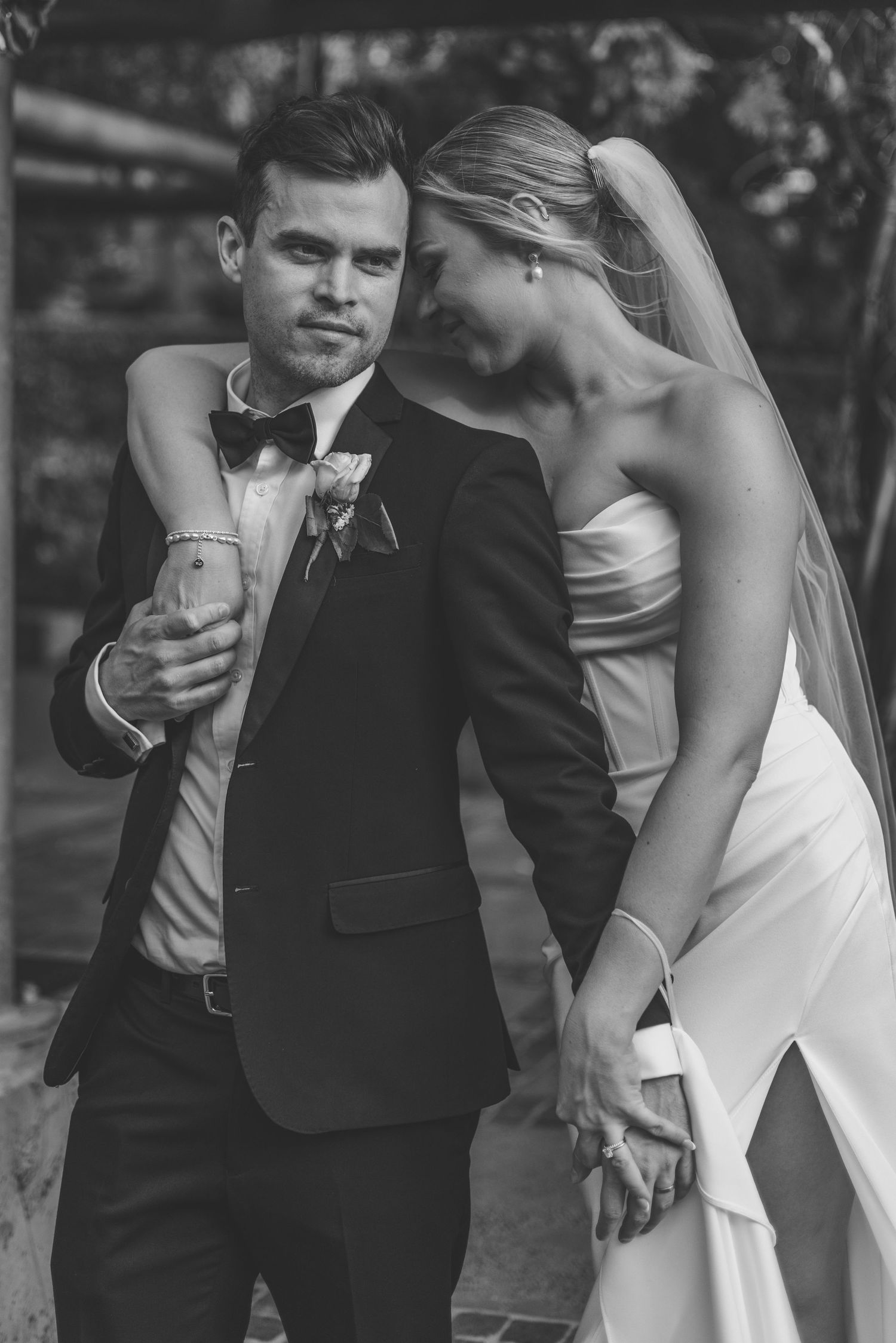 A black and white wedding photo showing a couple in formal attire, with the bride in white and groom in tuxedo.