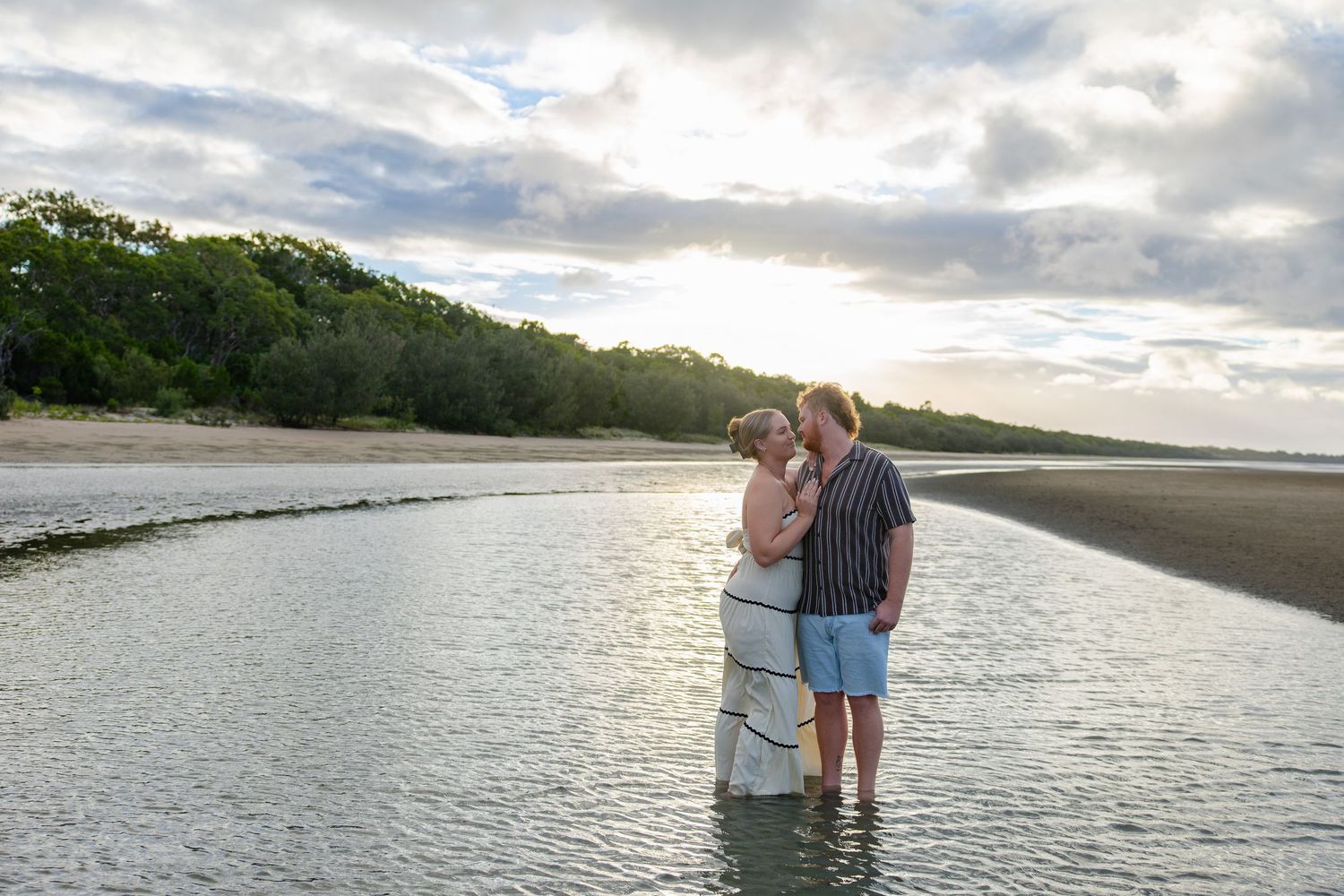 Couple sharing romantic moments at sunset along a peaceful beach shoreline.