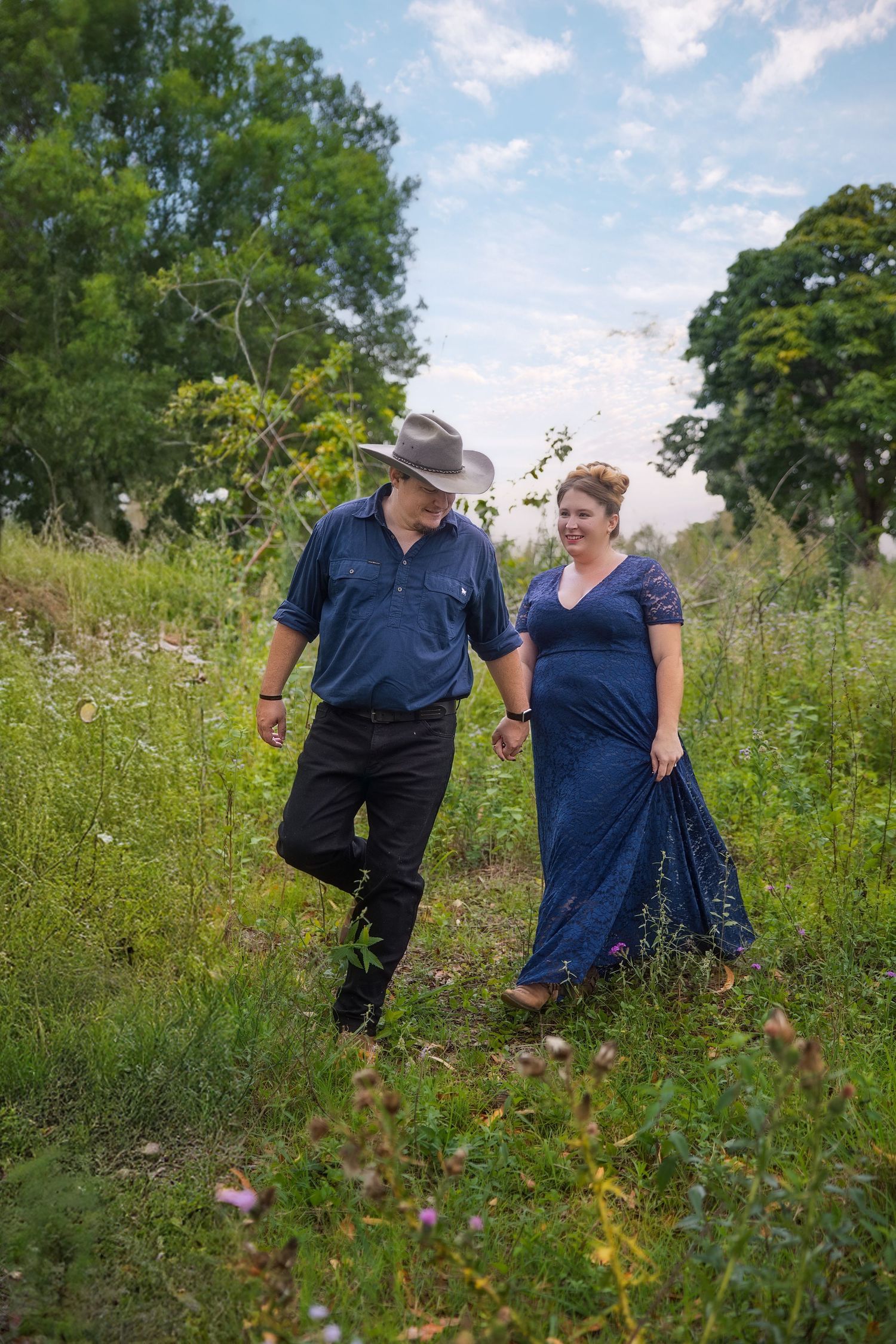 A couple walks together through a scenic wildflower meadow on a sunny summer afternoon.