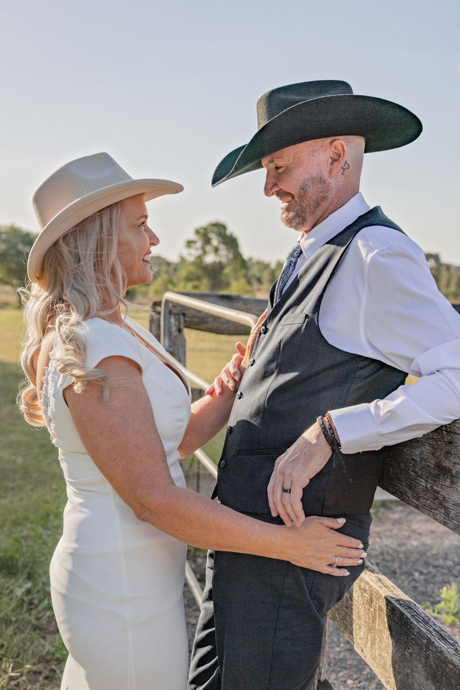 A couple in western attire shares intimate moments during their outdoor photo session at sunset.