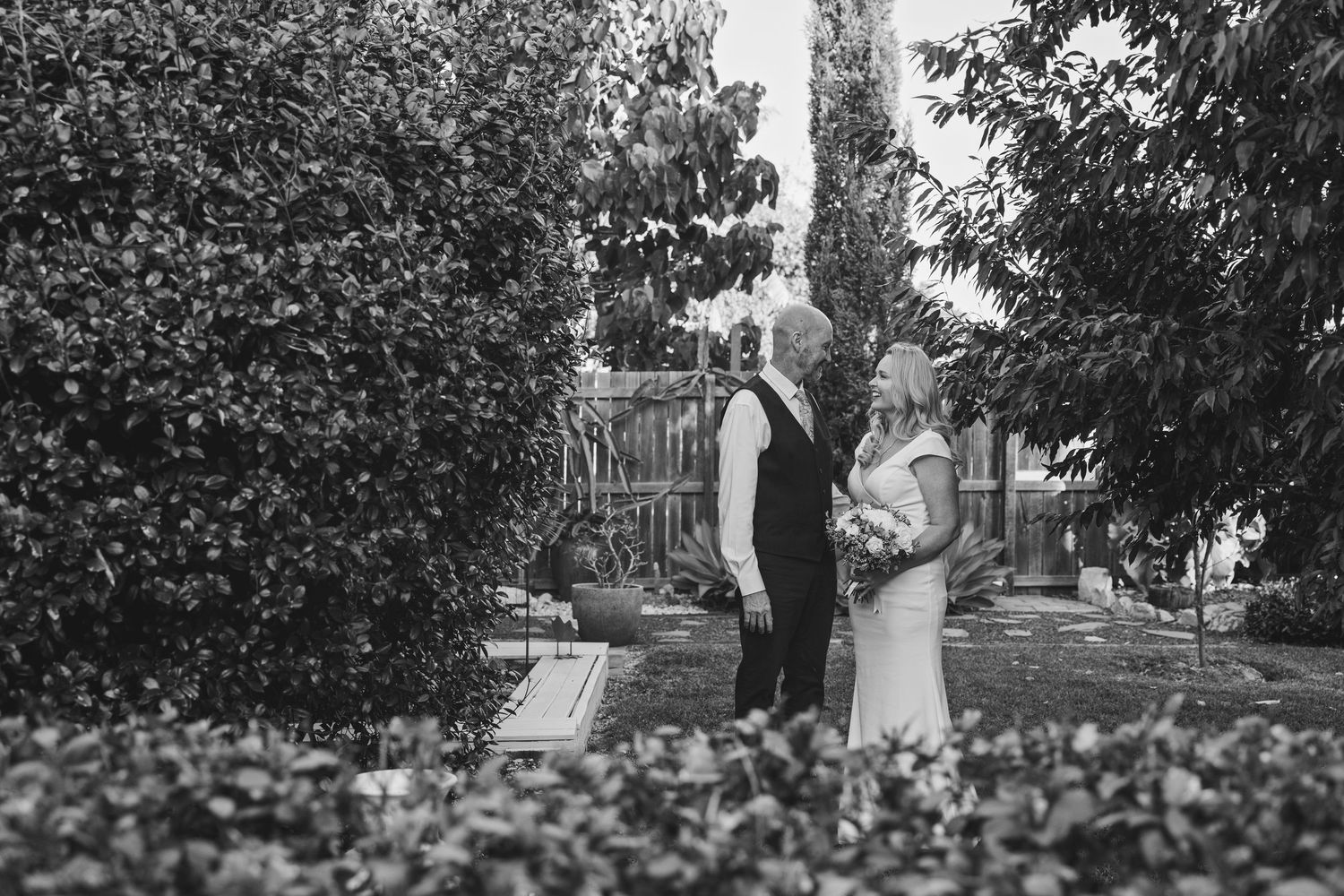 A black and white photo series shows a couple in formal wedding attire posing together in a garden setting.