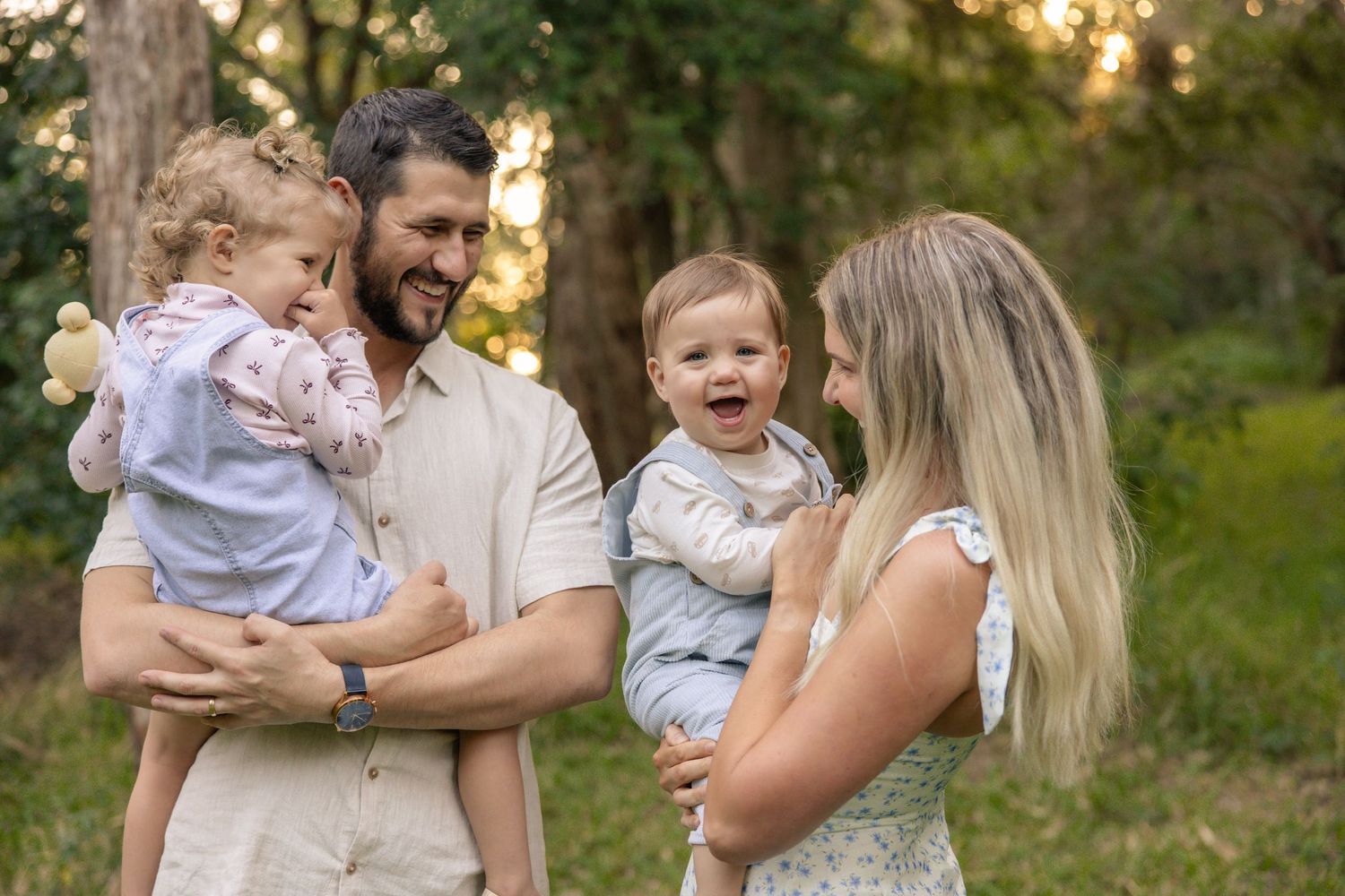 A happy family shares a joyful moment together outdoors during golden hour in a natural park setting.