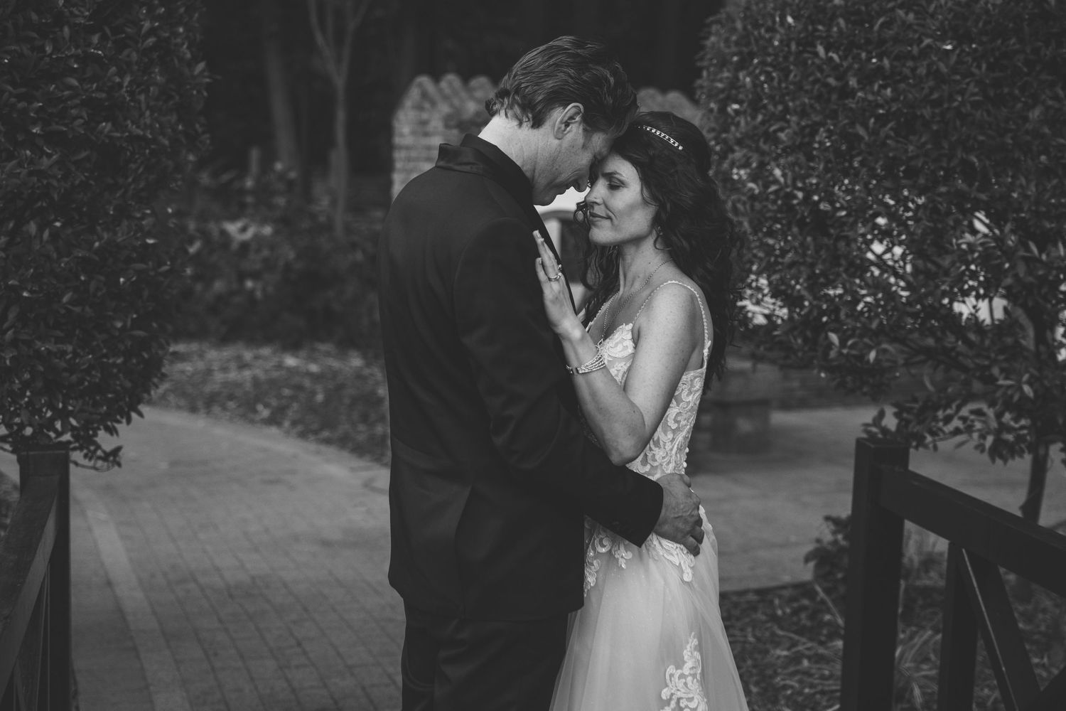 A romantic black and white wedding photo series showing intimate moments between newlyweds in an outdoor garden setting.