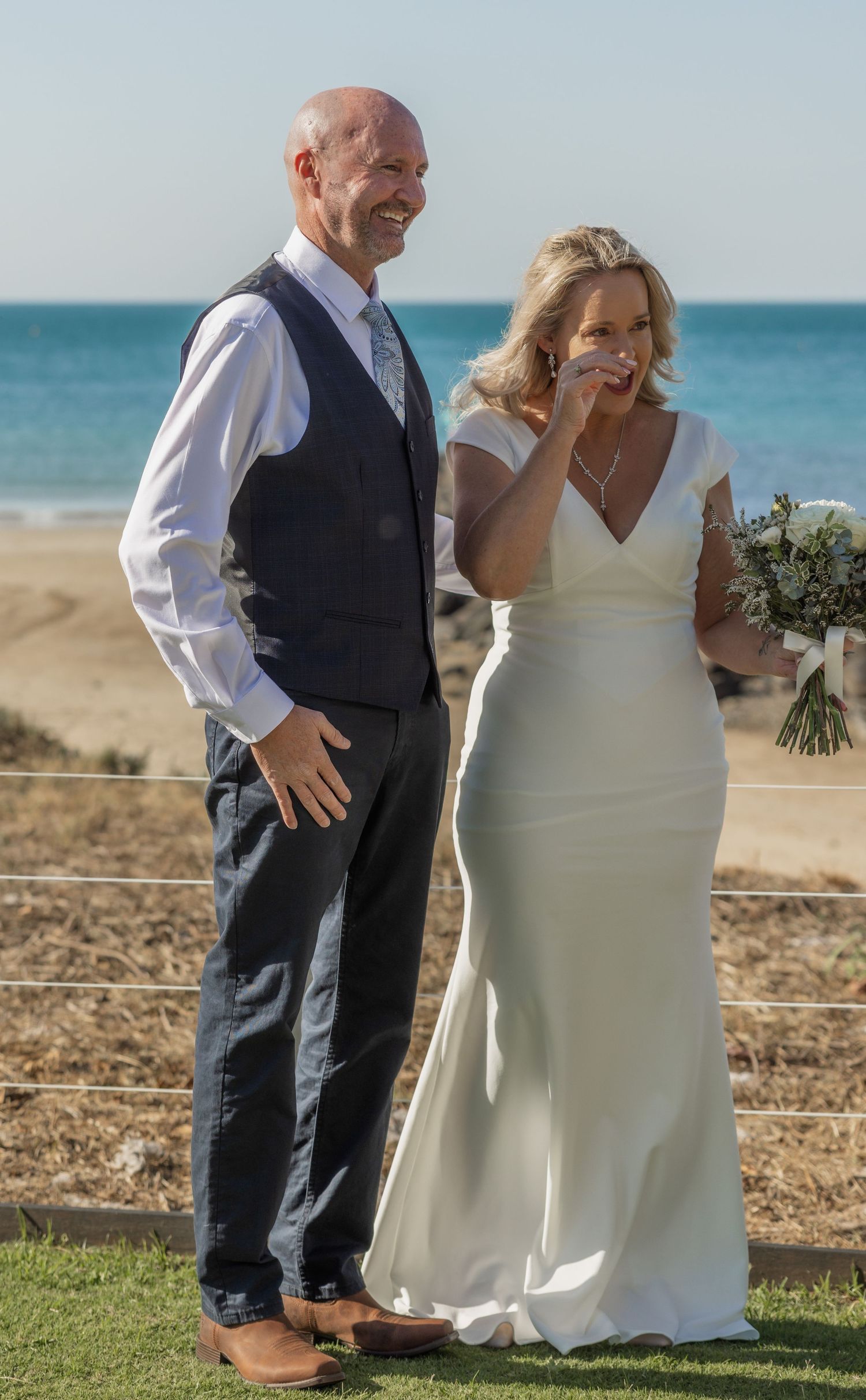 A couple shares a joyful moment together during their beach wedding ceremony on a sunny day.
