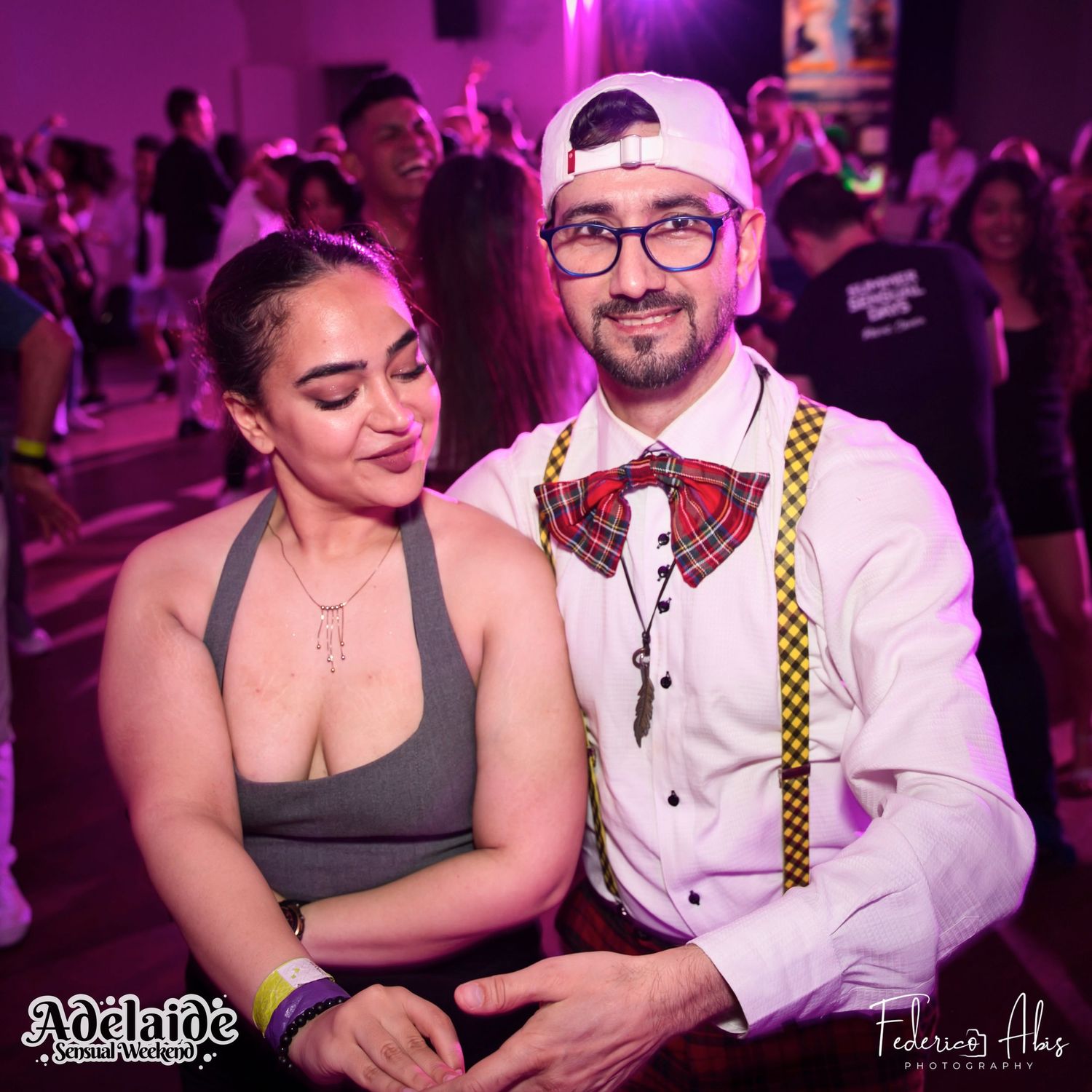 A couple enjoying themselves at a dance party with pink ambient lighting.