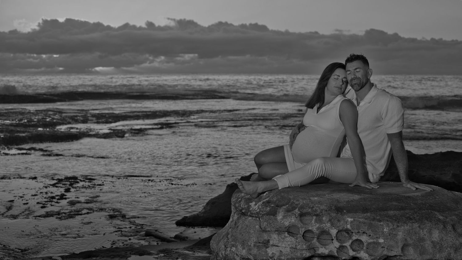 Romantic seaside portrait on rocky beach at dusk.