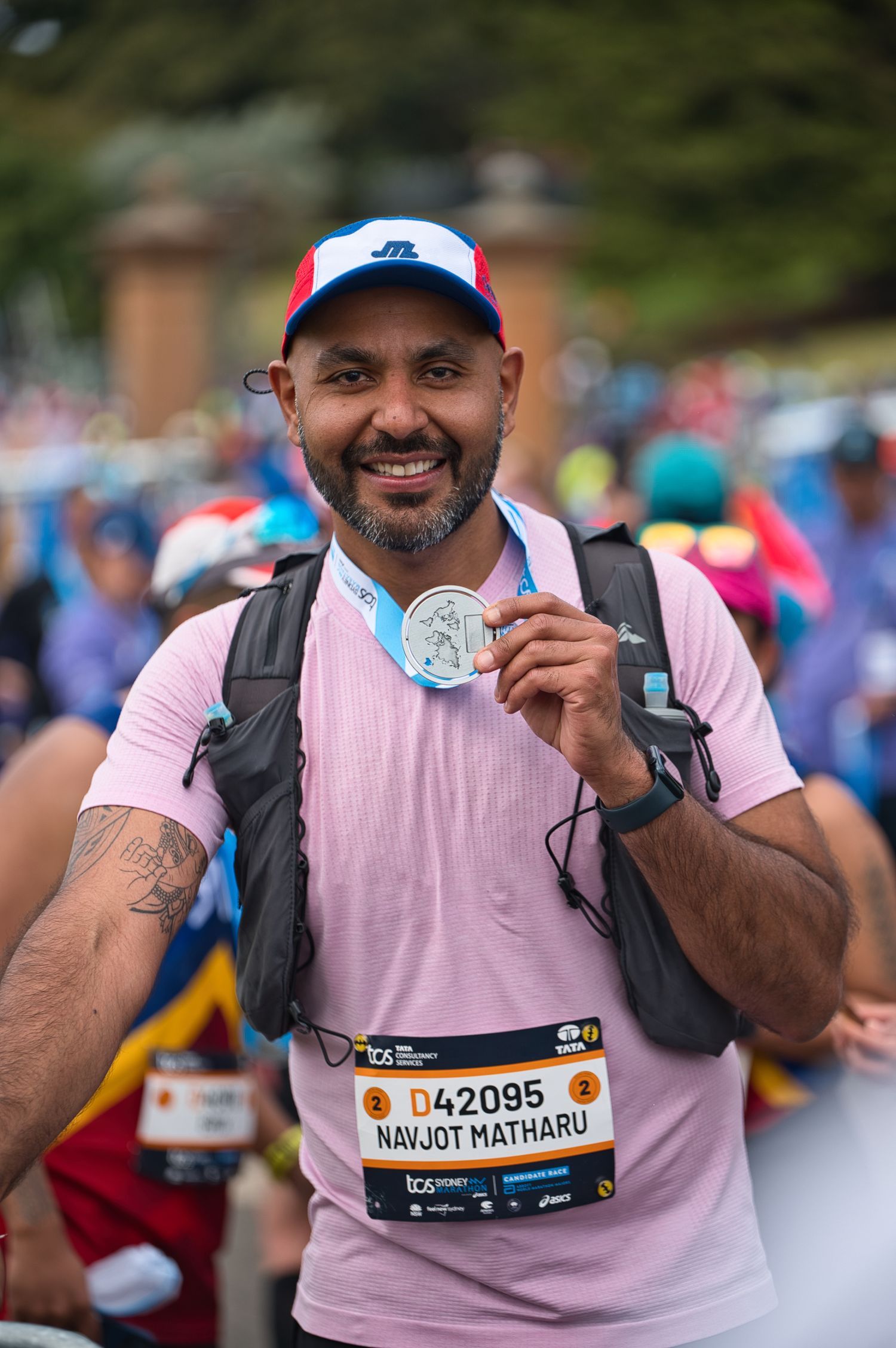 Runner displays finisher medal while wearing pink shirt and race bib at marathon event.