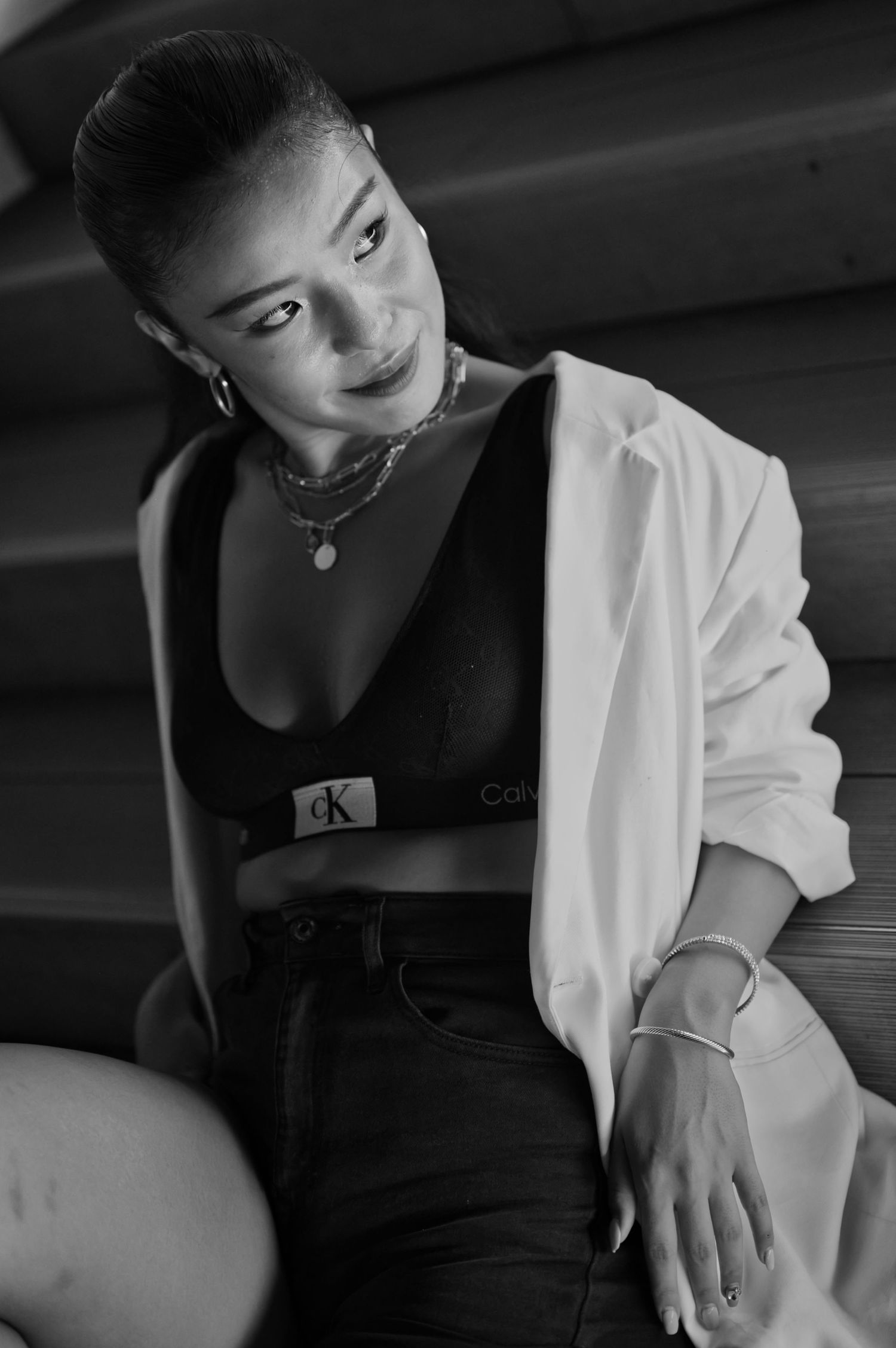 A dramatic black and white fashion portrait with white blazer and jewelry styling.