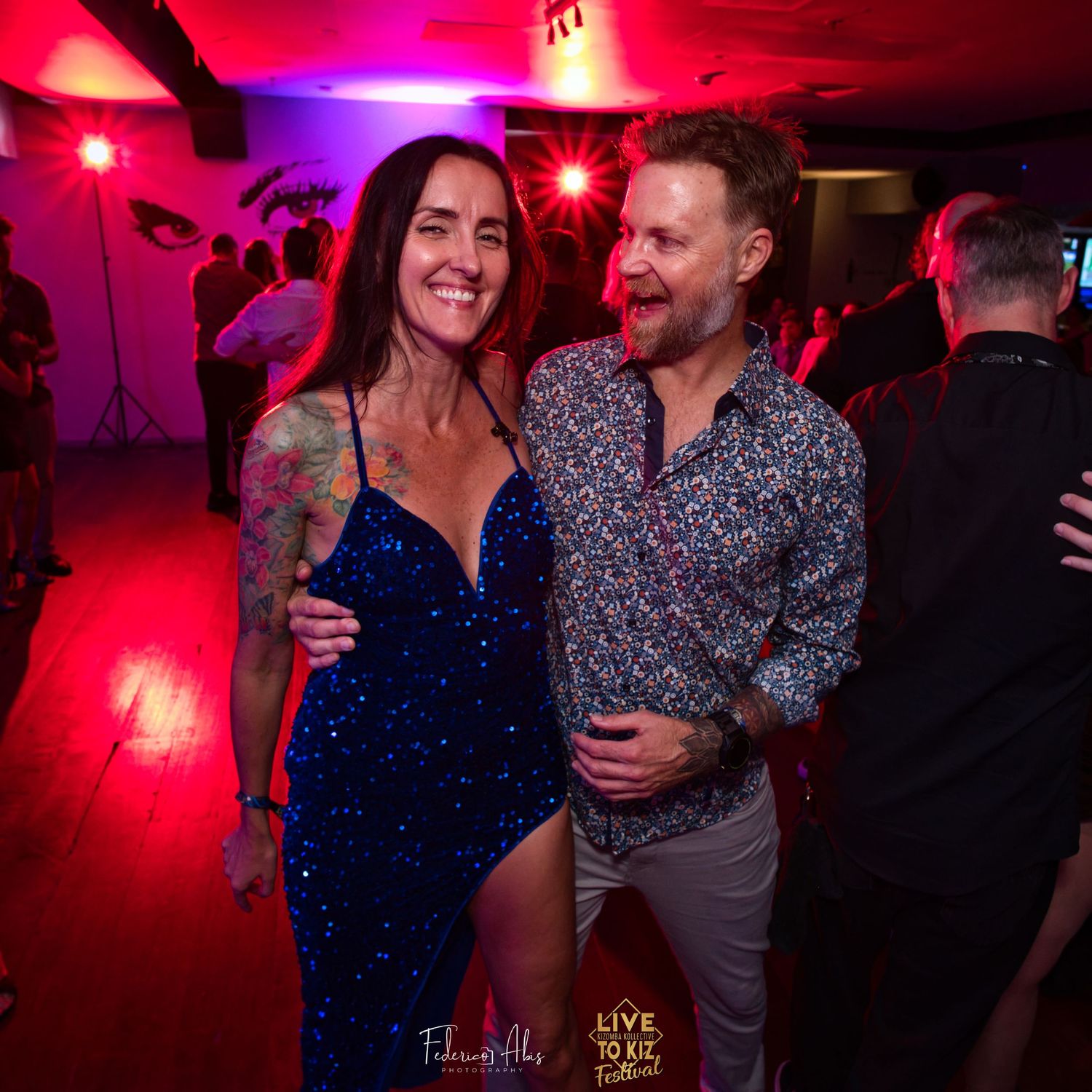Couple enjoying nightclub atmosphere under red and purple lighting.