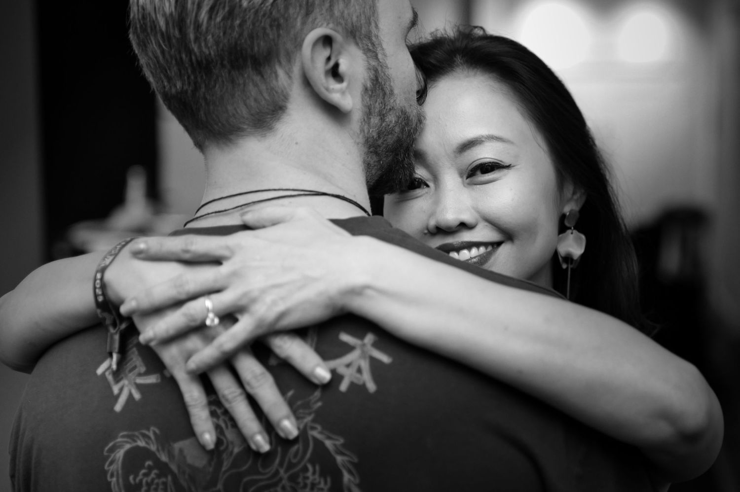 Black and white intimate embrace showing tattoo and emotional connection.