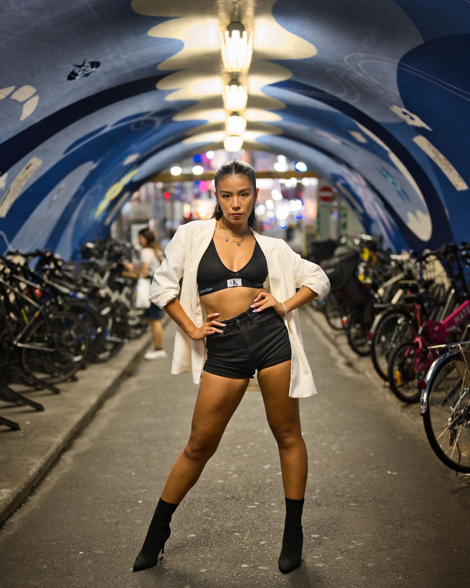 Athletic figure poses in a tunnel bike storage area with dramatic lighting and arched ceiling.