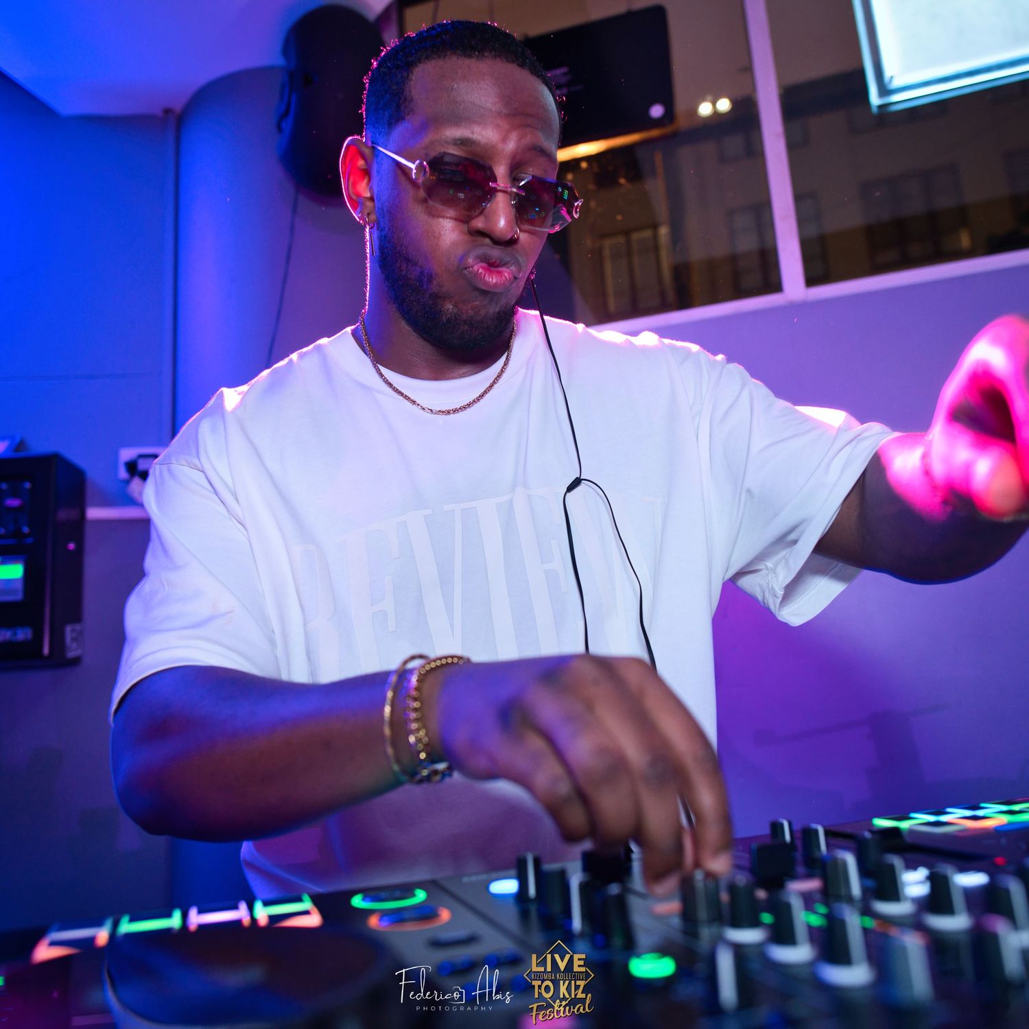DJ performing at nightclub with blue lighting and professional equipment.