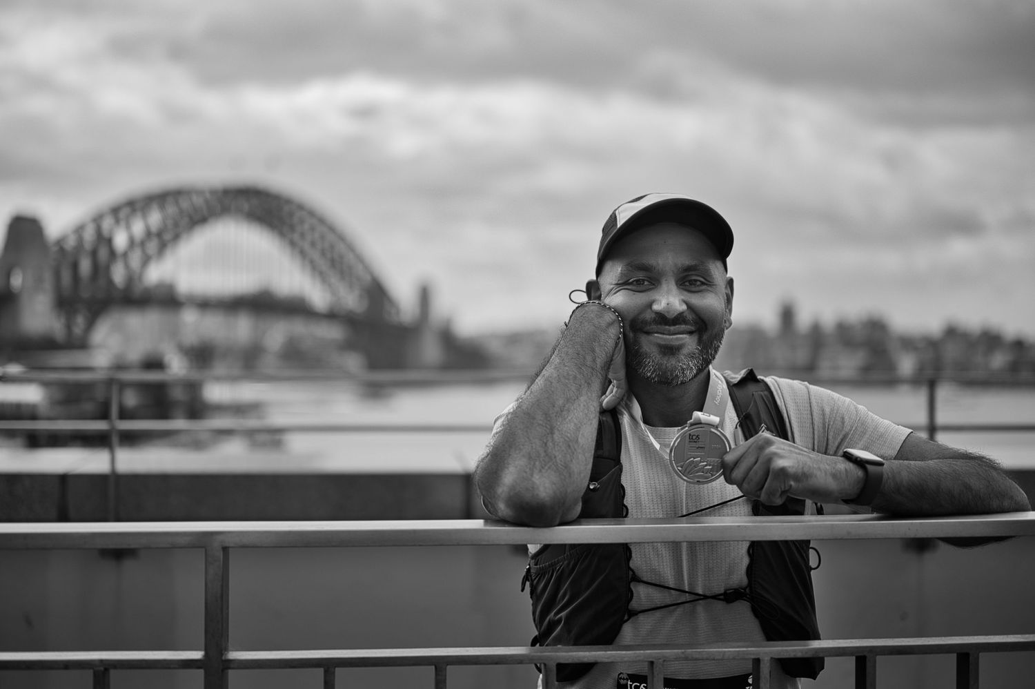 Black and white portrait with Sydney Harbour Bridge visible in background on cloudy day.