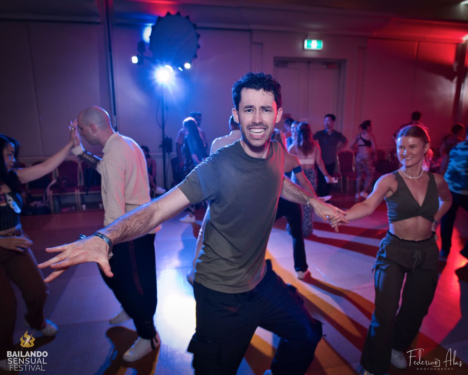 Dancer expressing joy while moving on a dance floor with blue lighting effects.