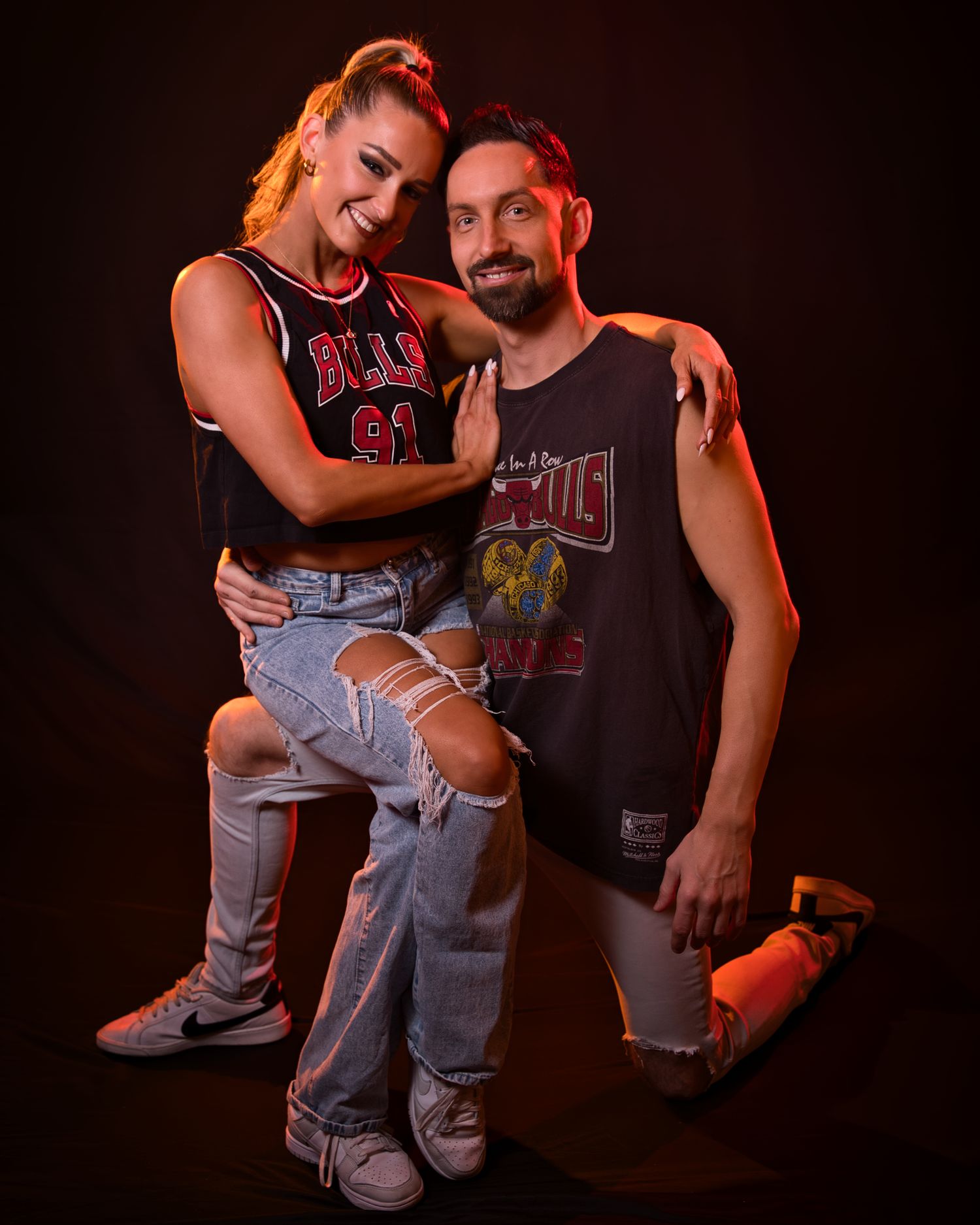 Casual portrait of two people in rock band t-shirts against dark background.