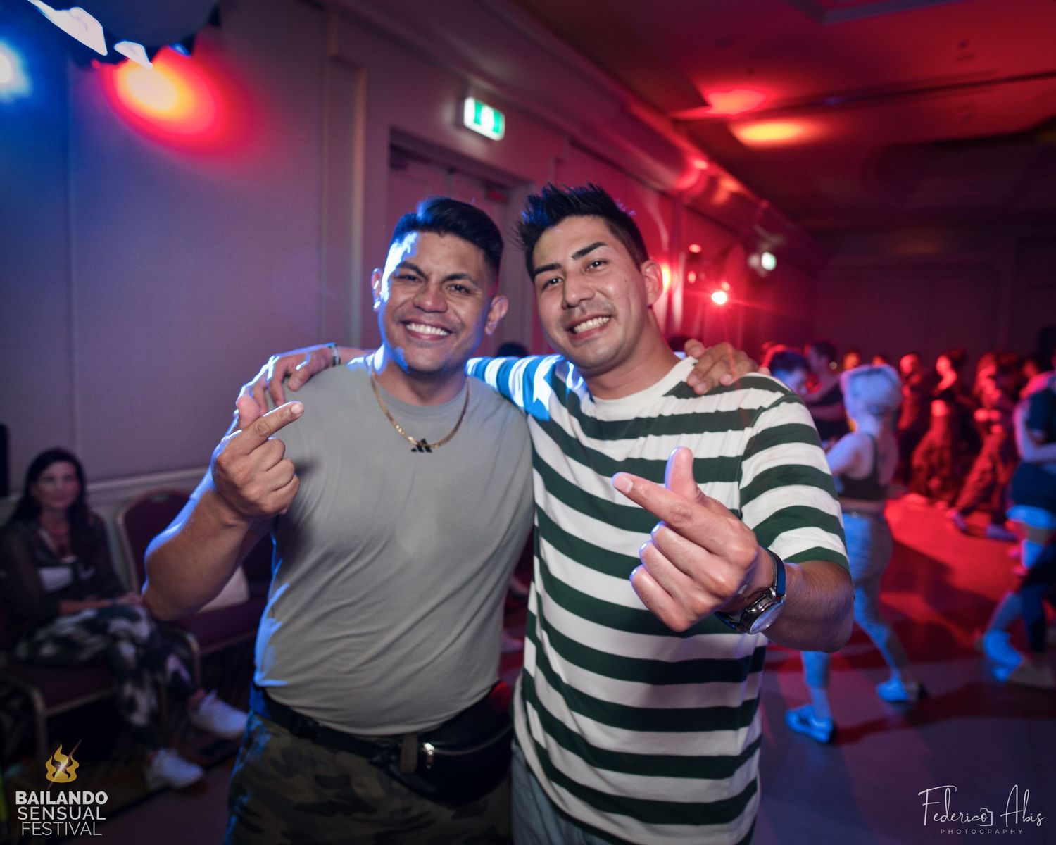 Two friends posing for a photo at a dance social with party lighting in the background.